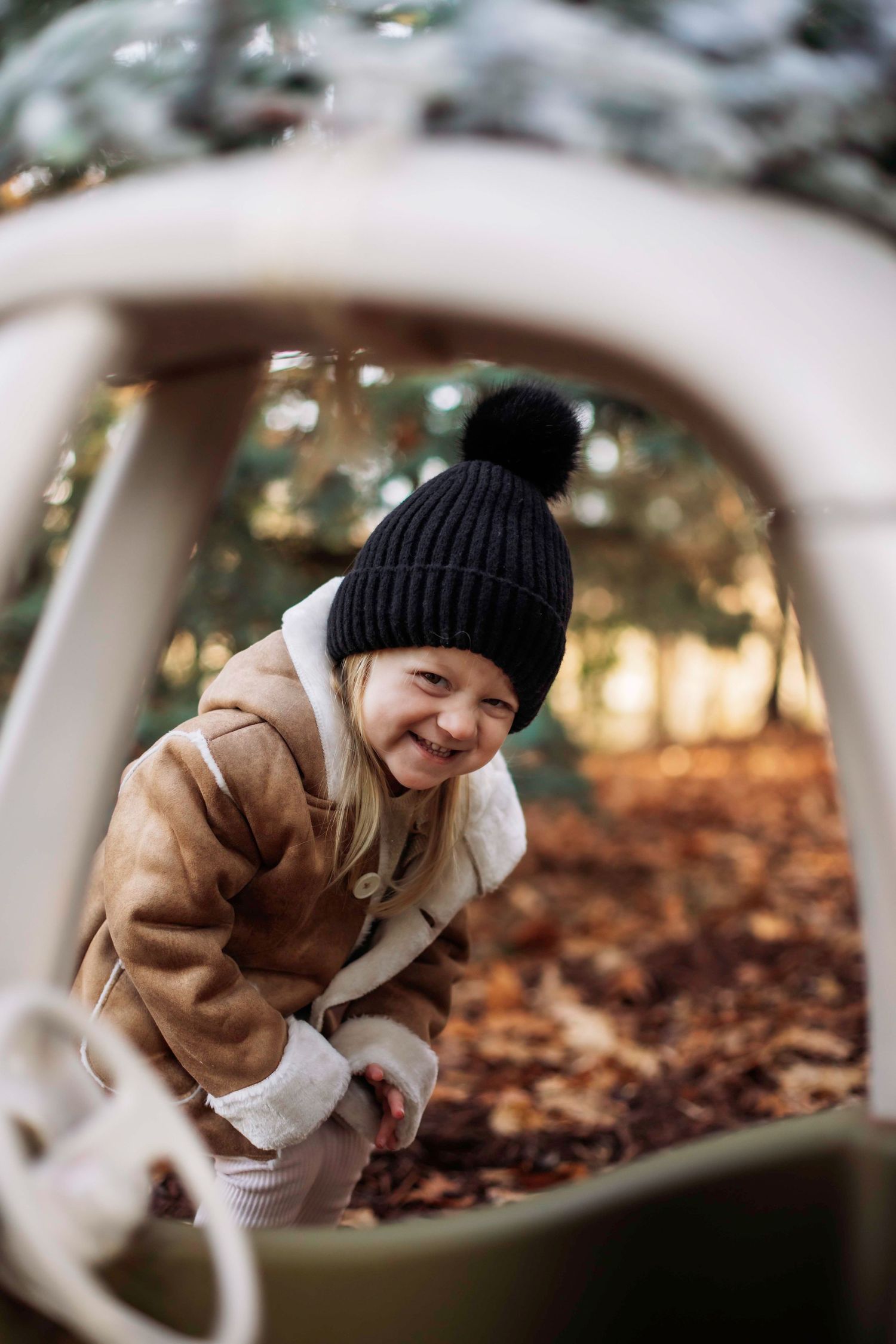 Candid shot through cozy coupe window of child laughing in winter coat and beanie.