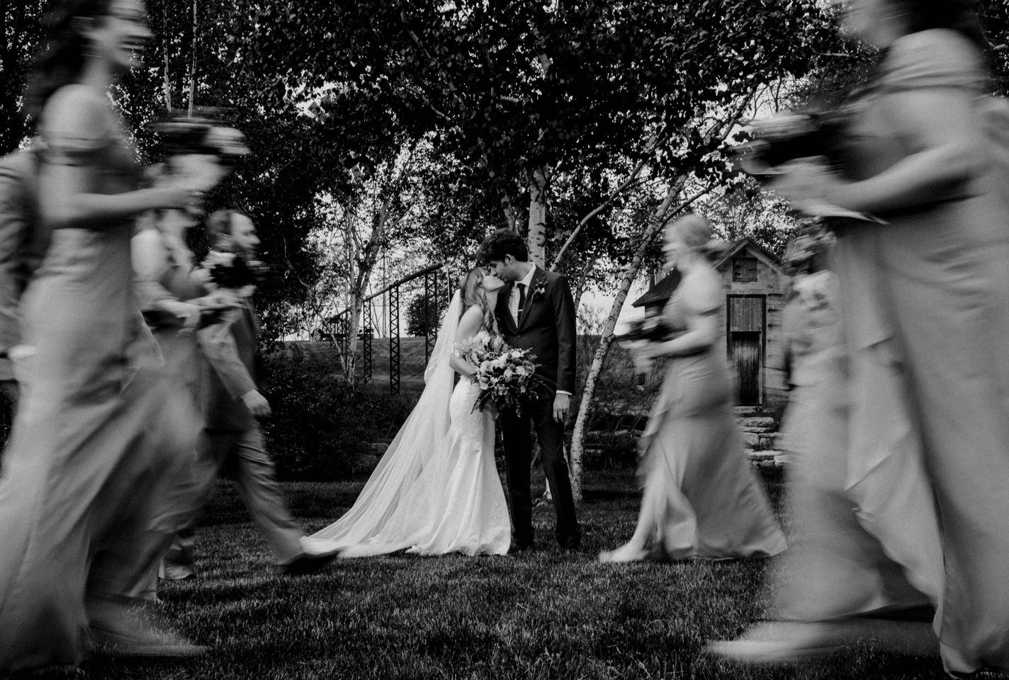 An artistic black and white wedding photo with motion-blurred guests creating a dreamy atmosphere.
