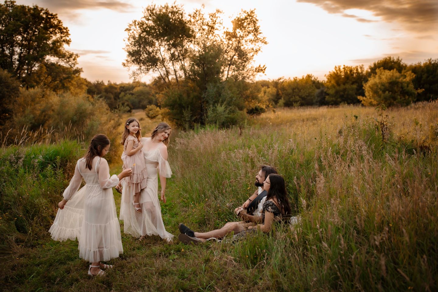 People gather in a golden meadow at sunset for an intimate outdoor photoshoot.