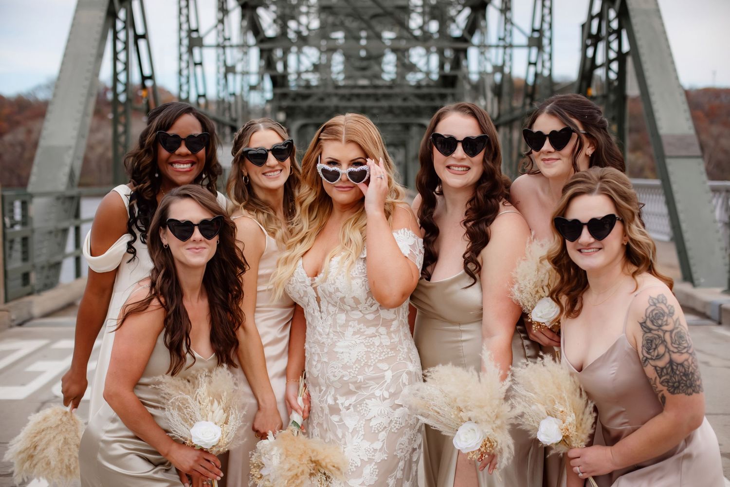 Wedding party wearing sunglasses pose for fun photo on industrial bridge.