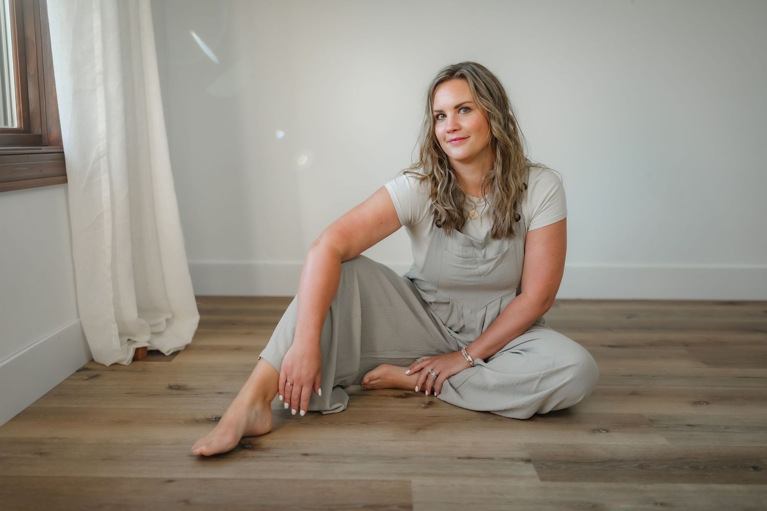 Casual portrait of person in gray loungewear sitting on hardwood floor.