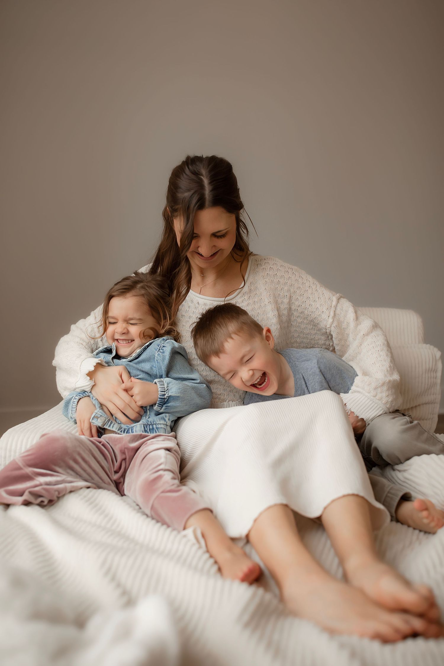 A heartwarming sequence of family cuddles and laughter on a cozy white bed with soft pillows and blankets.