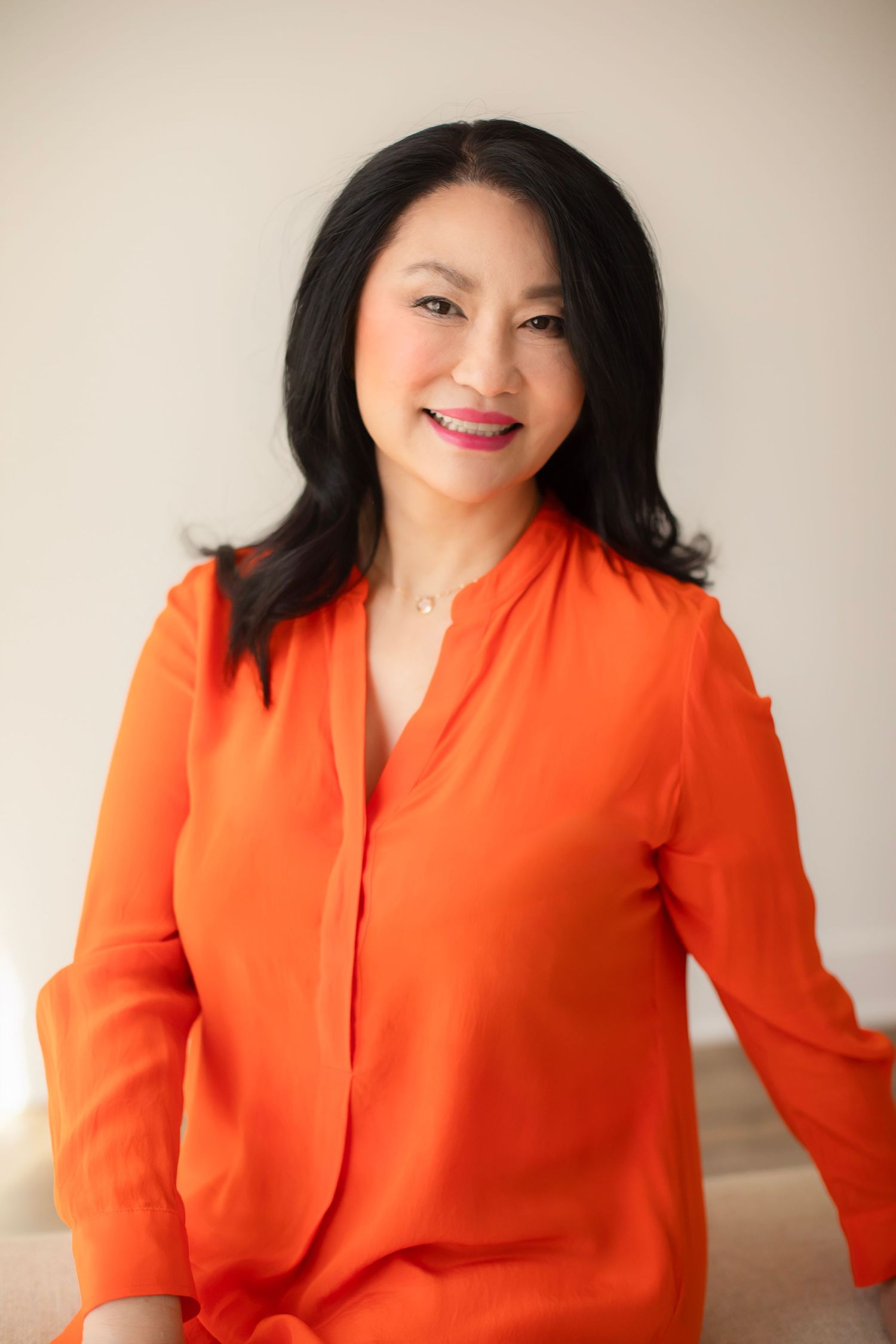 A series of portraits featuring someone wearing a bright orange blouse against a light colored backdrop.