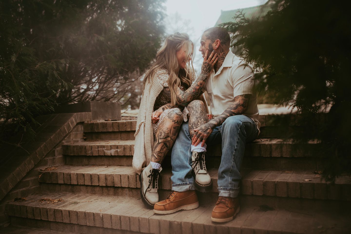 A couple shares an intimate moment while sitting on outdoor stone steps at sunset.