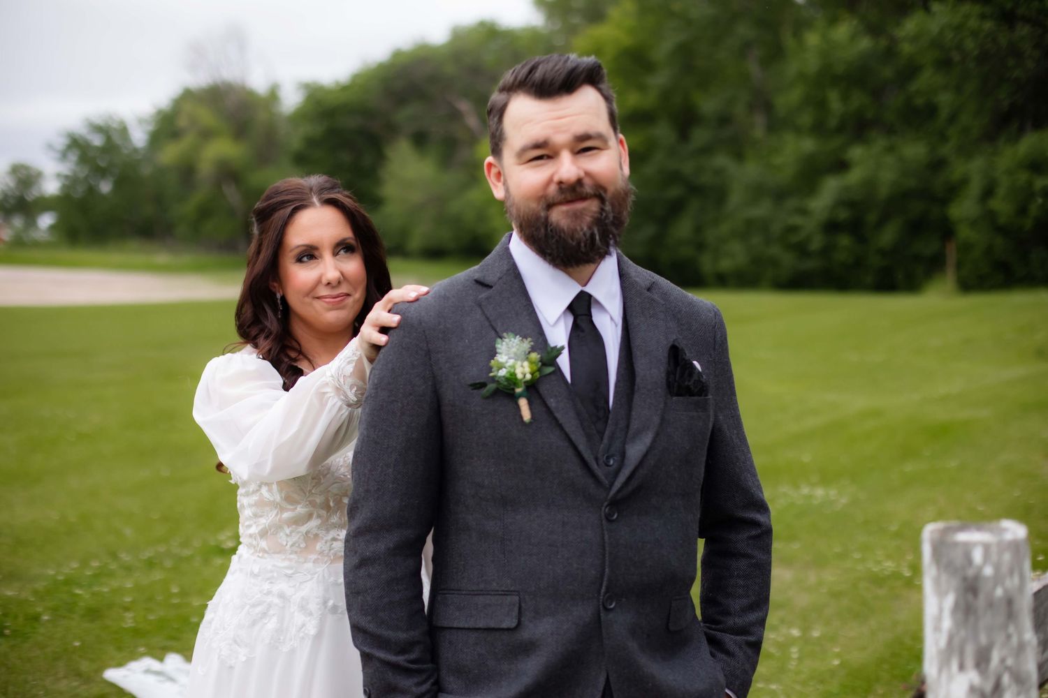 A bride and groom share a joyful moment together on a grassy lawn during their outdoor wedding celebration.