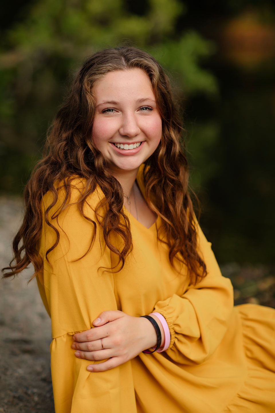 Portrait in mustard yellow sweater with natural woodland background.