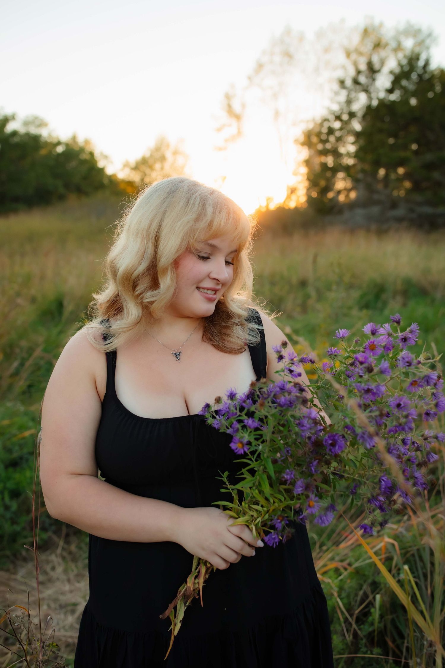 Portrait with purple wildflowers during sunset in natural setting.