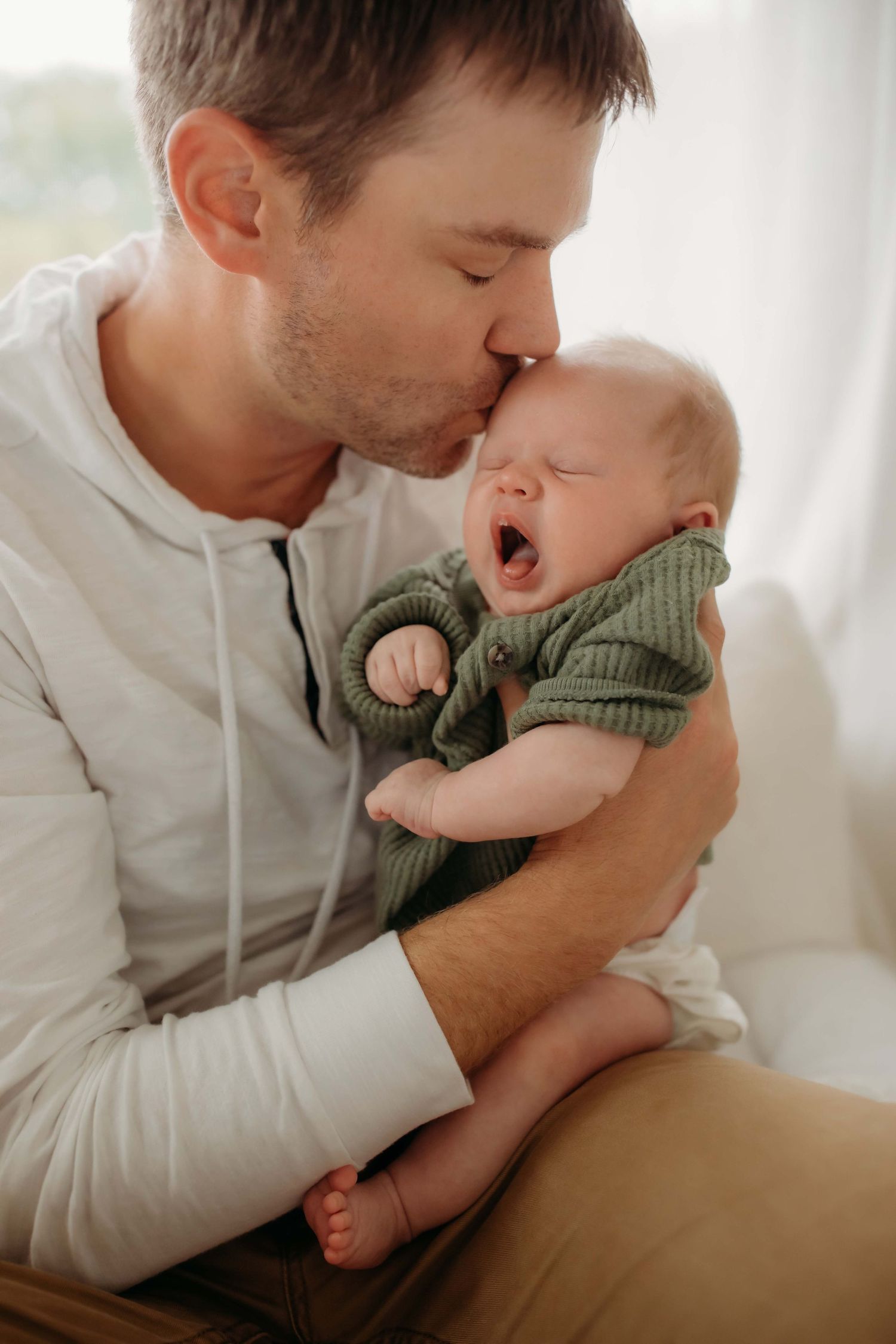 Tender moment between parent and baby wearing green sweater.