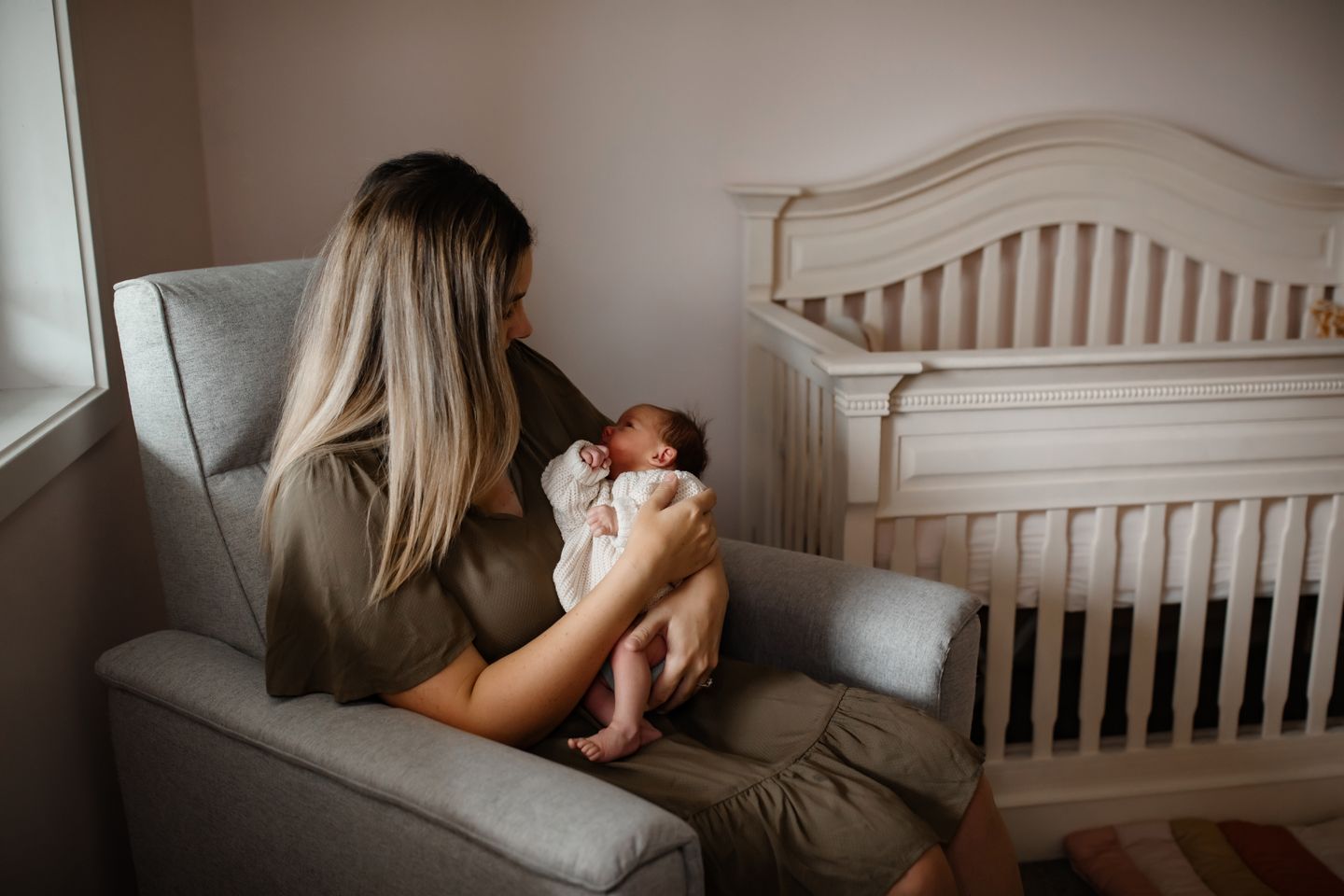 A cozy nursery scene with natural lighting streaming through the window beside a classic wooden crib.