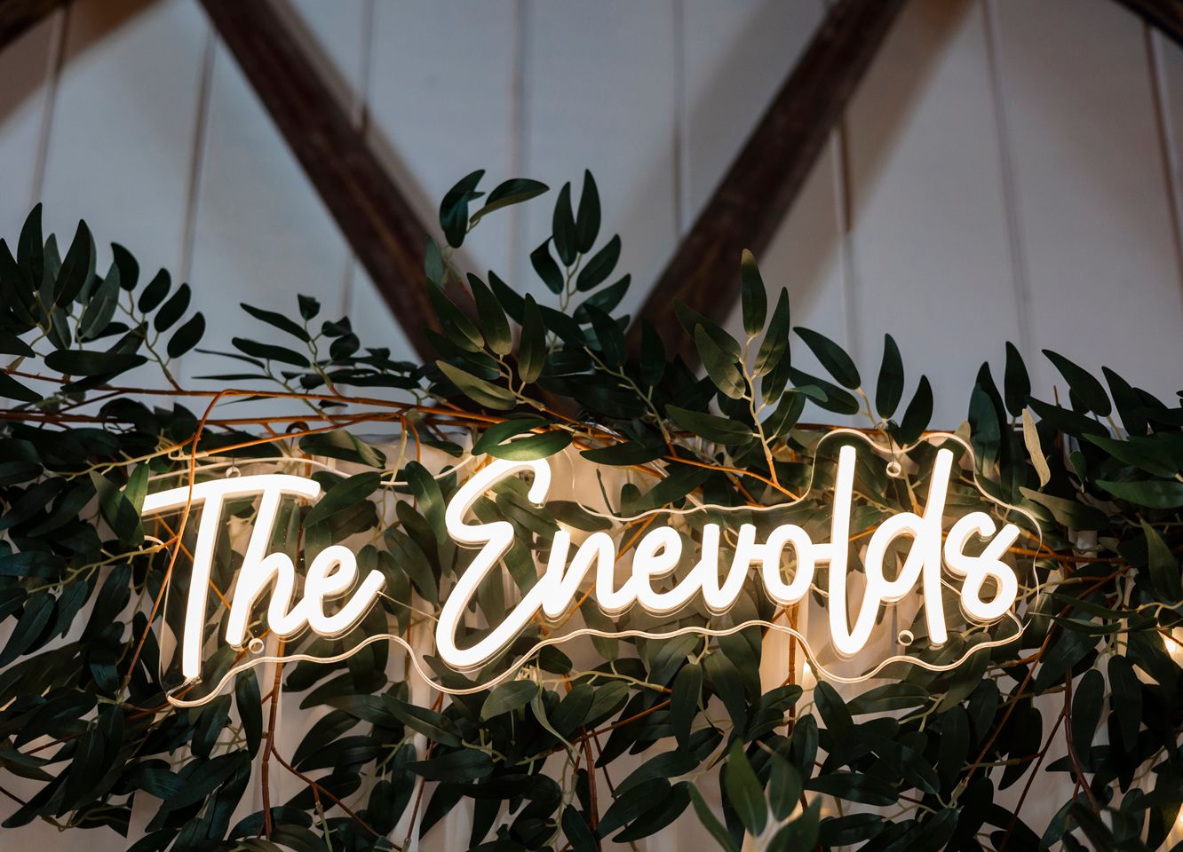 Illuminated neon sign reading 'The Enevolds' decorated with elegant green foliage in Minnesota.