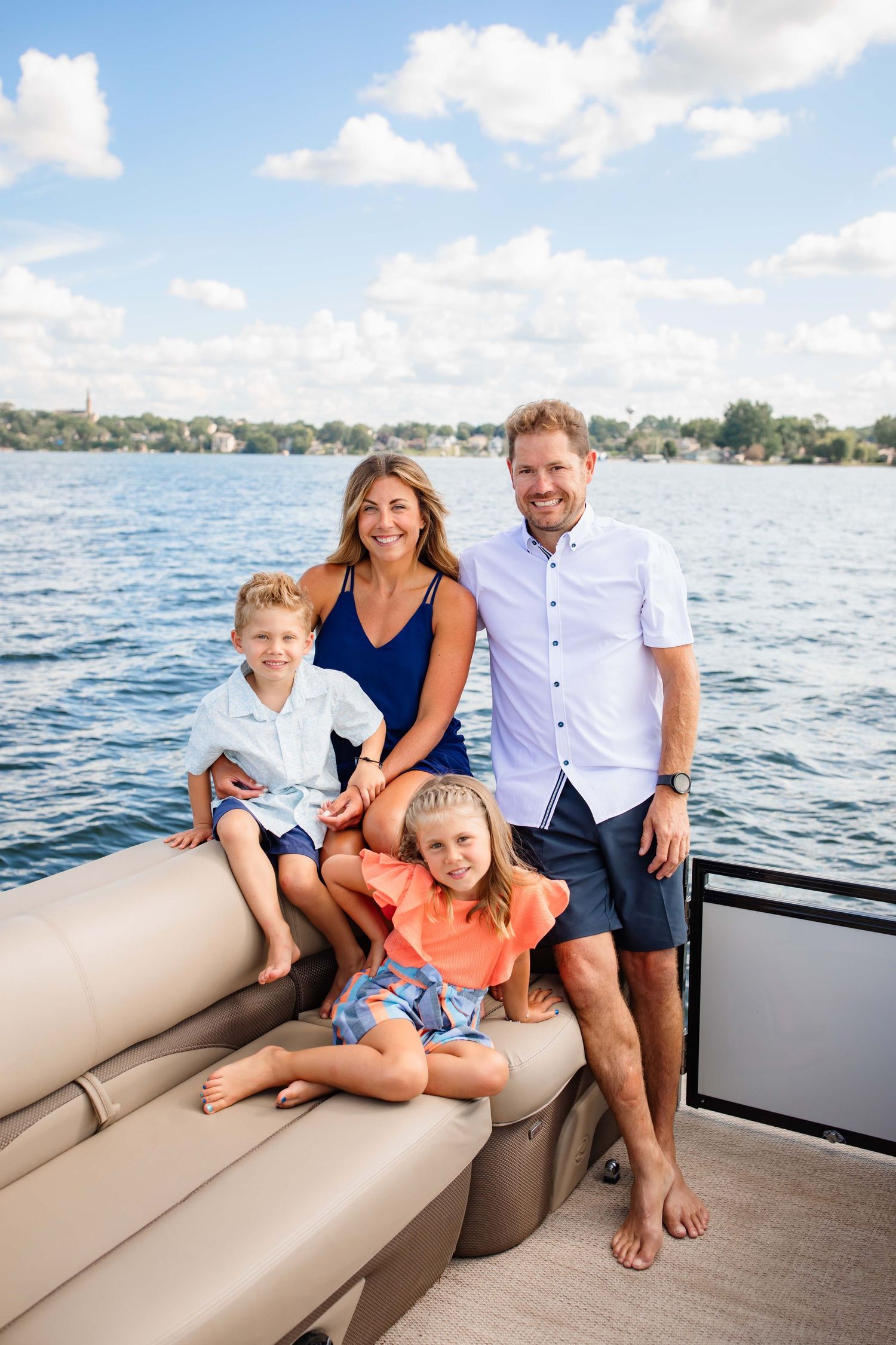 Family relaxing on boat cushions during sunny lake day outing.