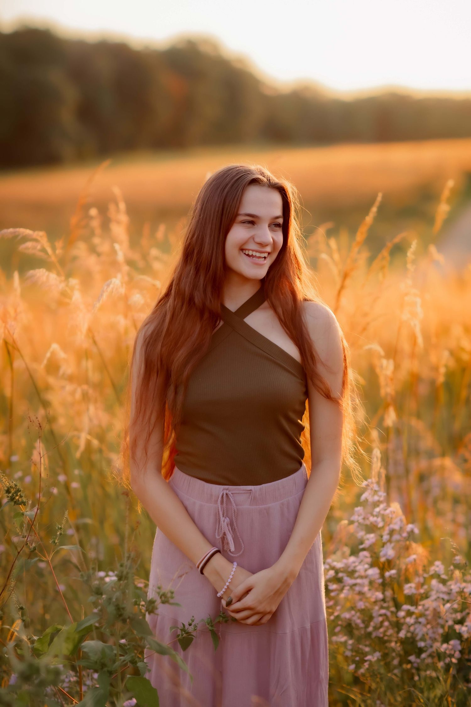 Sunset garden portrait in black top and mauve skirt surrounded by wildflowers.