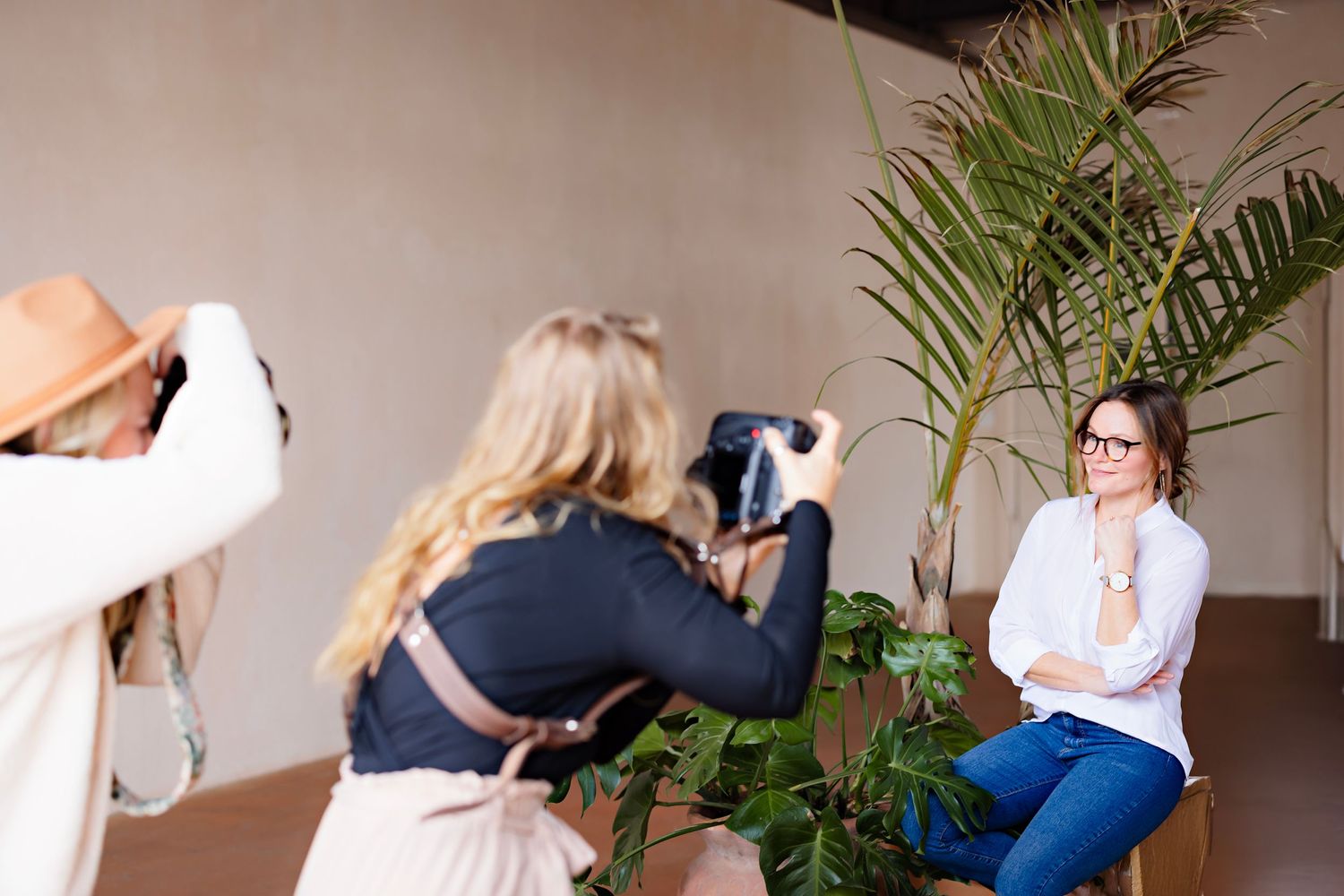 Indoor photography session with multiple cameras and a tropical plant setting.