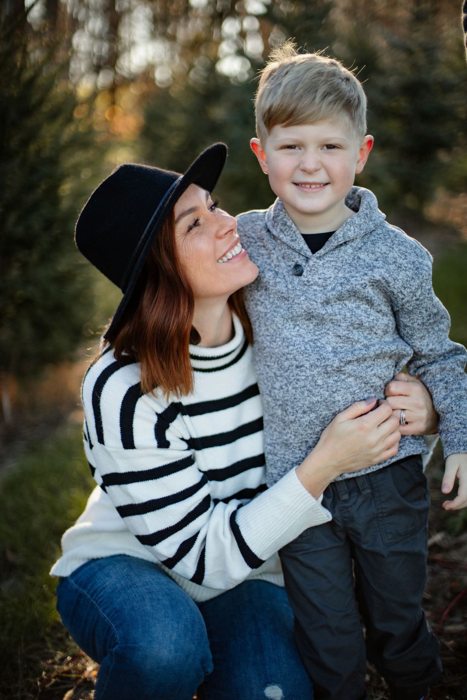 A tender moment captured between parent and child amongst evergreen trees.