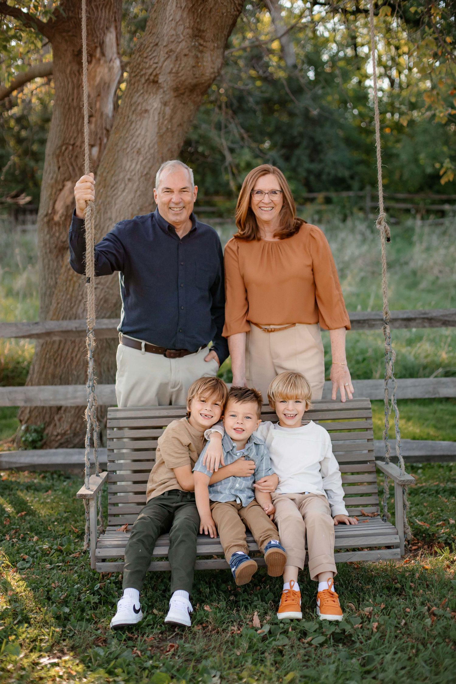Family relaxing on wooden swing in outdoor garden setting.