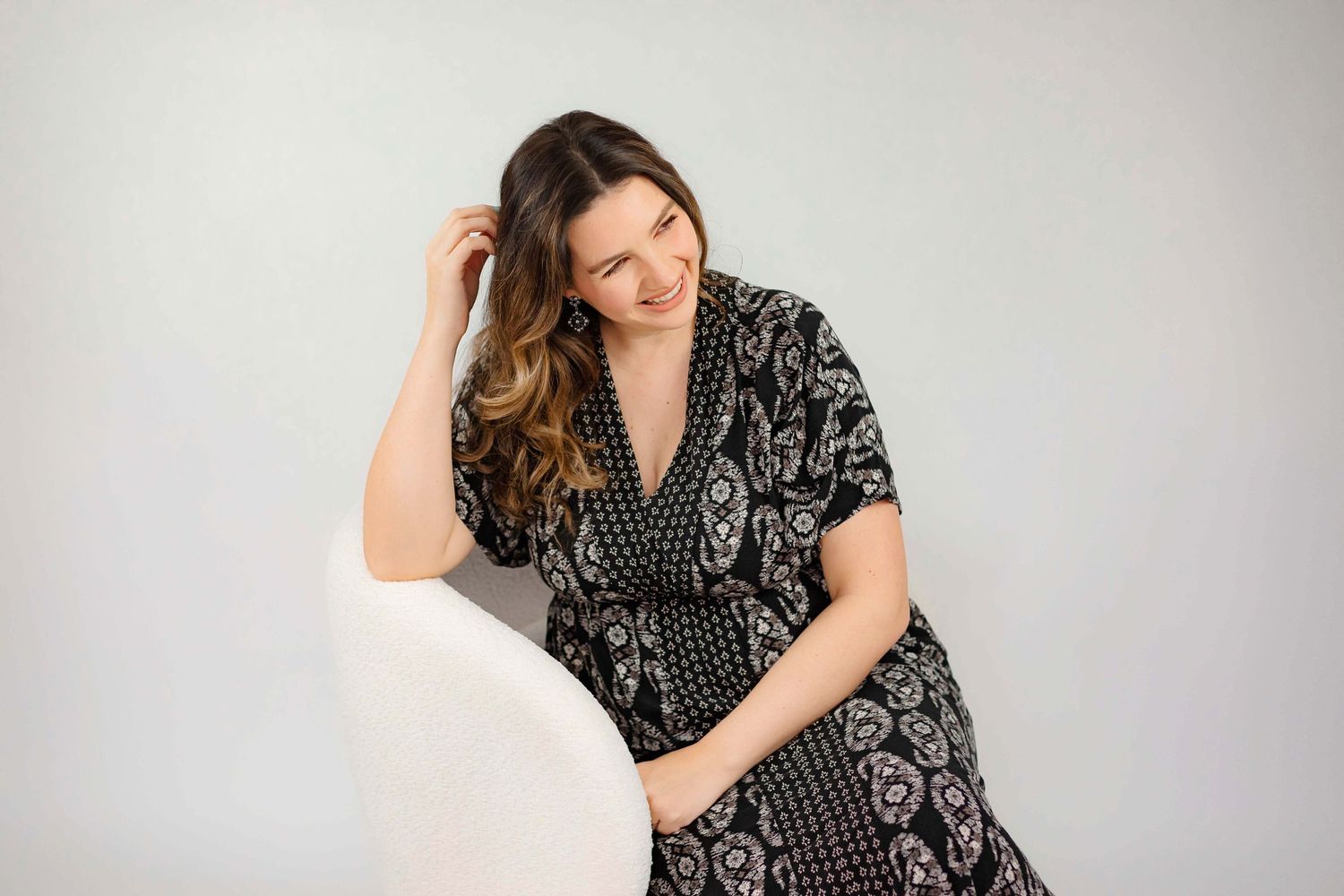 Relaxed portrait in patterned black and white wrap dress against white backdrop.