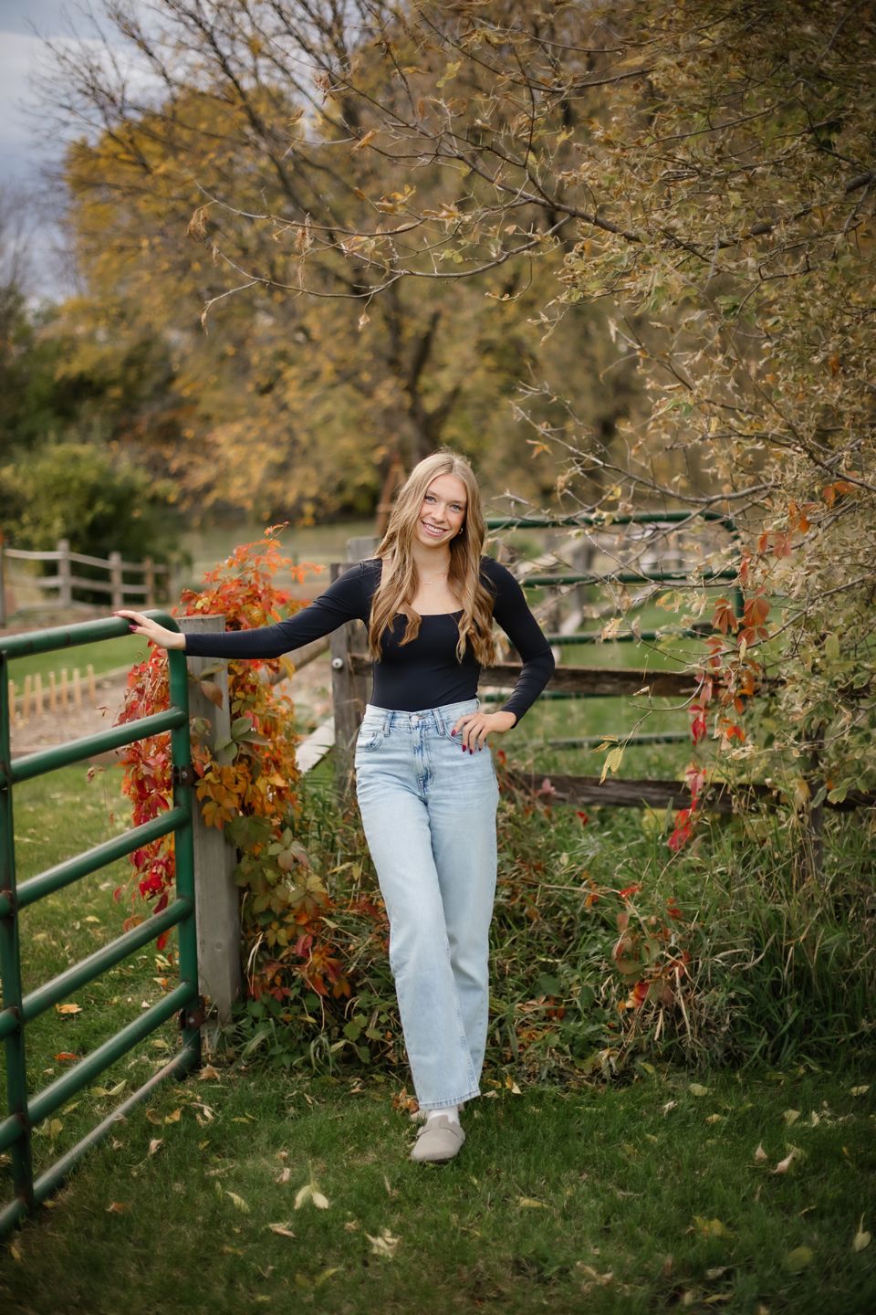 Casual fashion photo by a rustic fence surrounded by fall foliage and autumn colors.