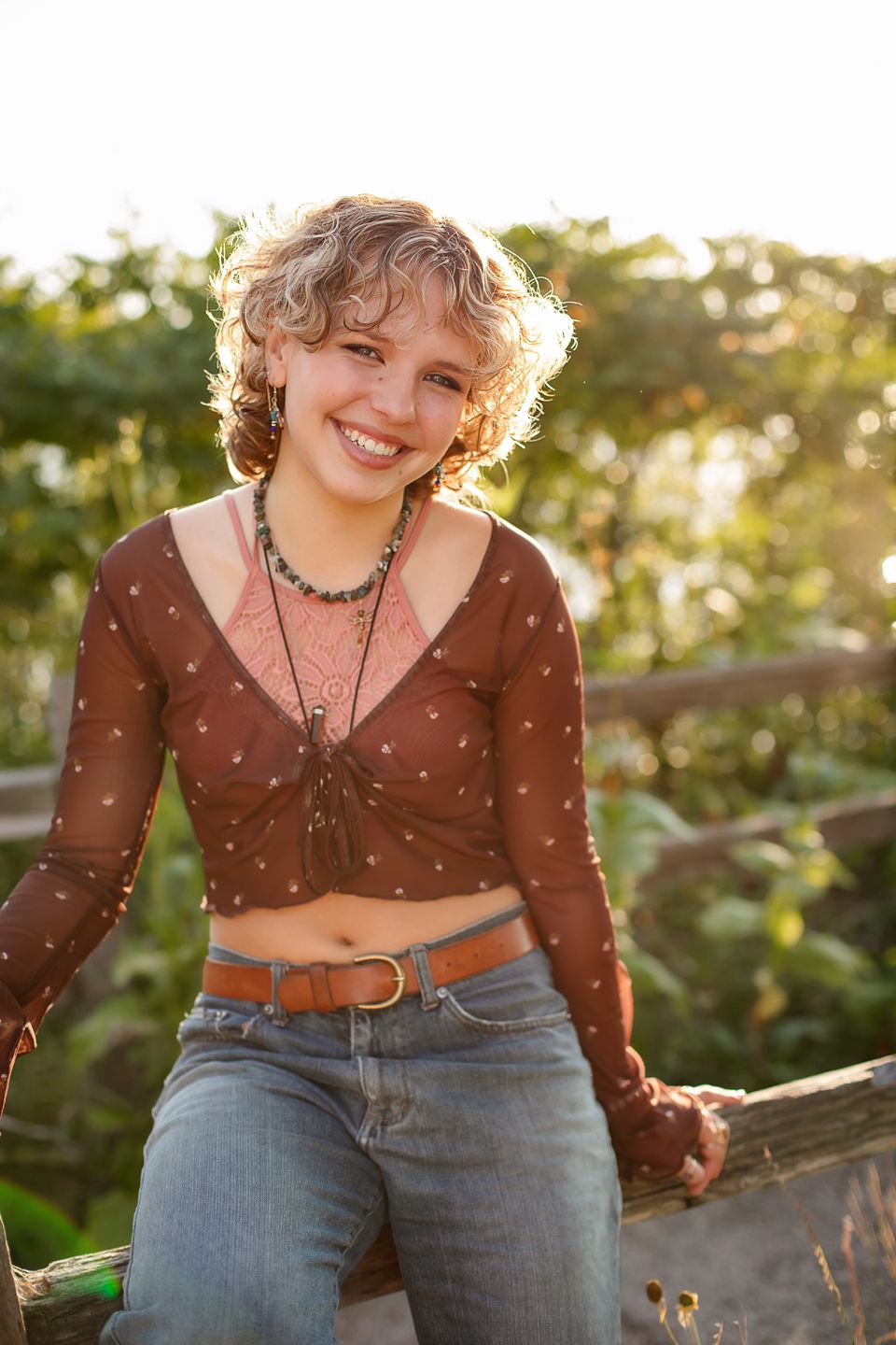 A brown polka dot top and jeans outfit photographed during golden hour with natural sunlit background.