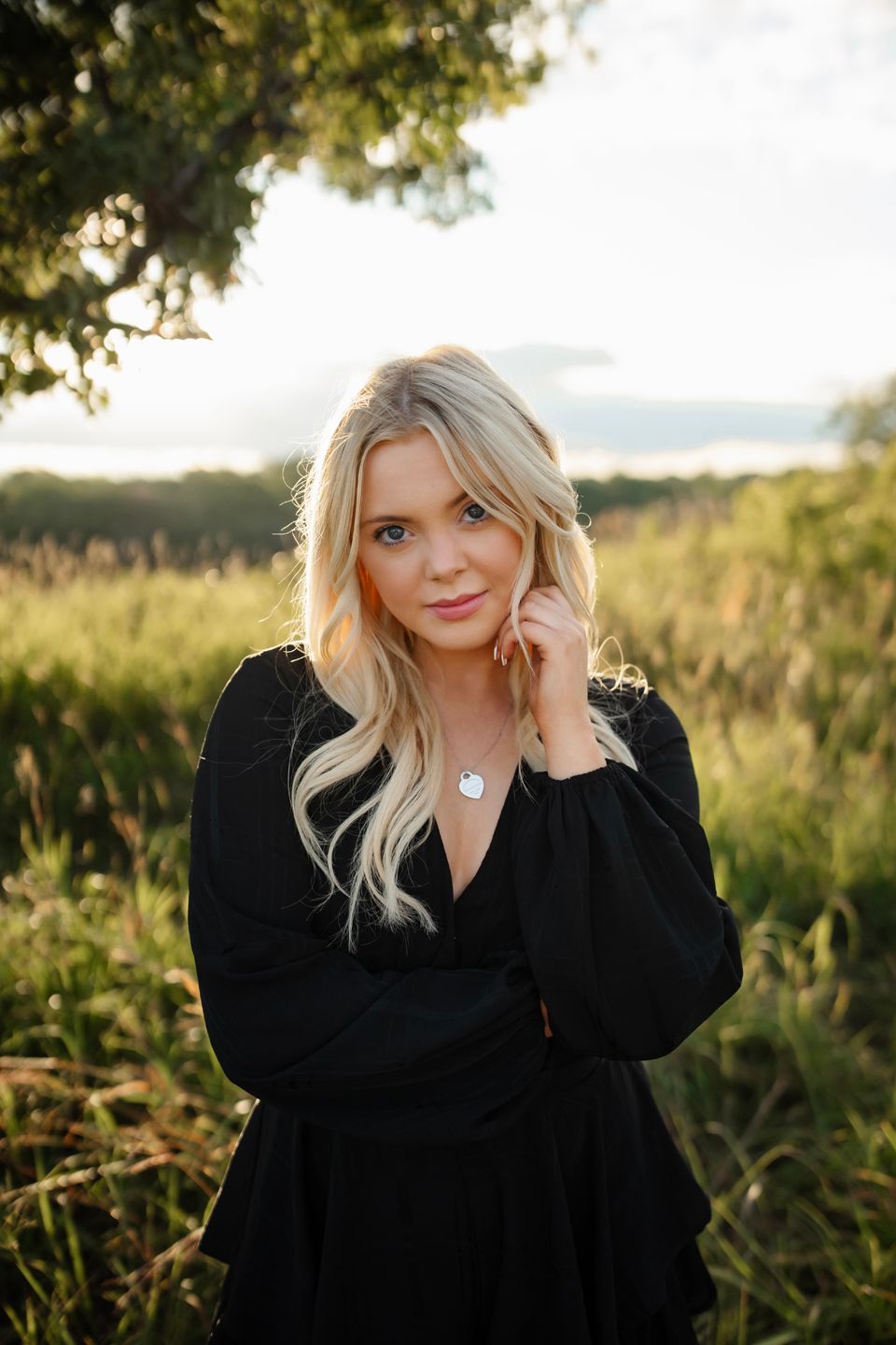 Outdoor portrait in black dress against natural golden hour landscape.