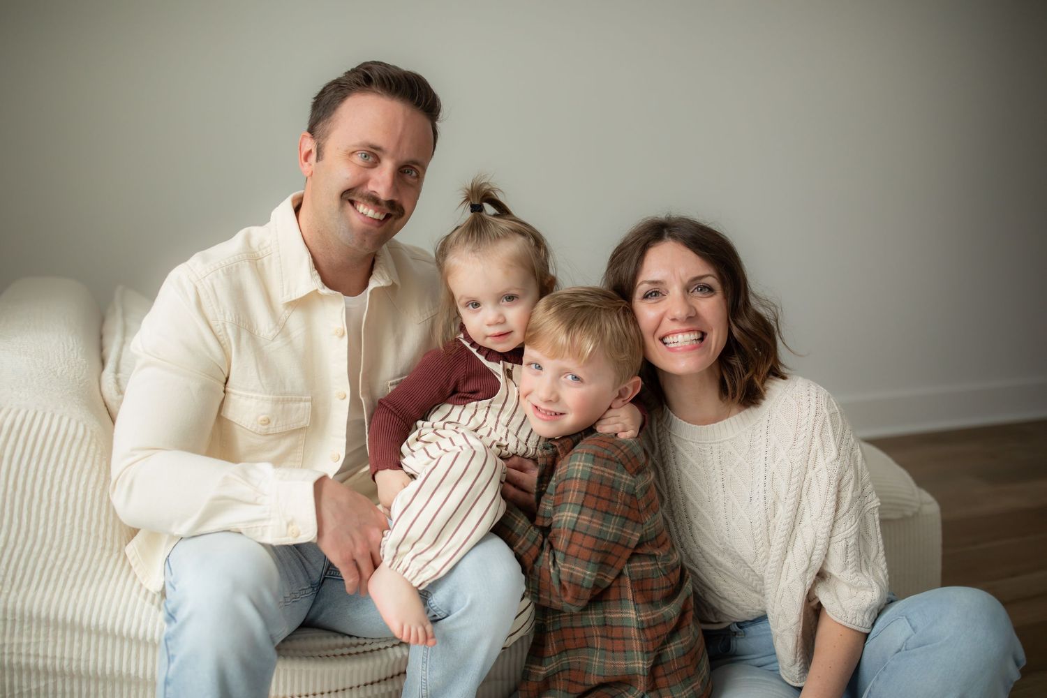Relaxed lifestyle photography session with a family wearing coordinated neutral colors on white furniture.