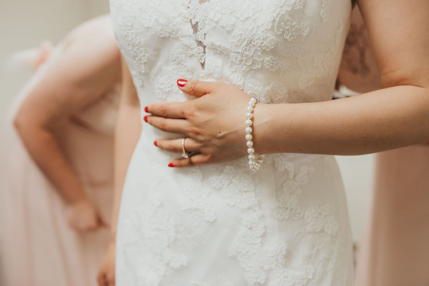 Close-up of bridal dress details showing pearl bracelet and lace bodice.