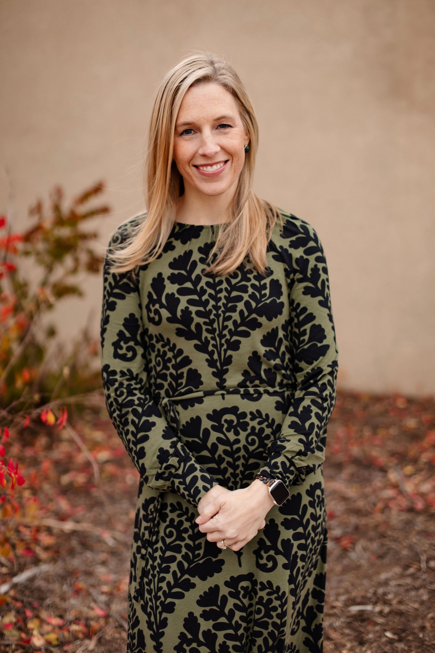 Outdoor portrait in olive and black damask dress with fall foliage in background.