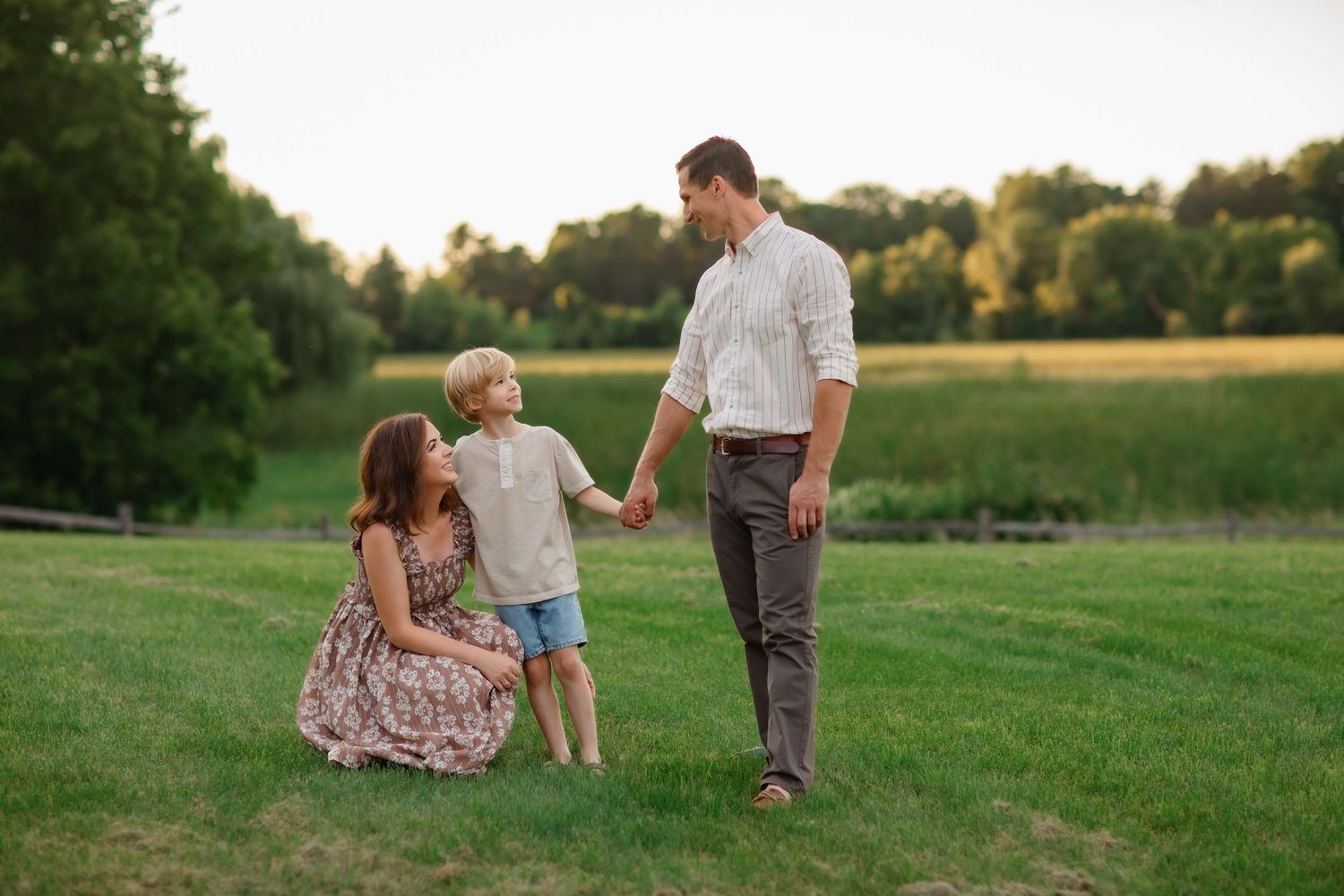 Beautiful outdoor family moment in a green summer field at golden hour.