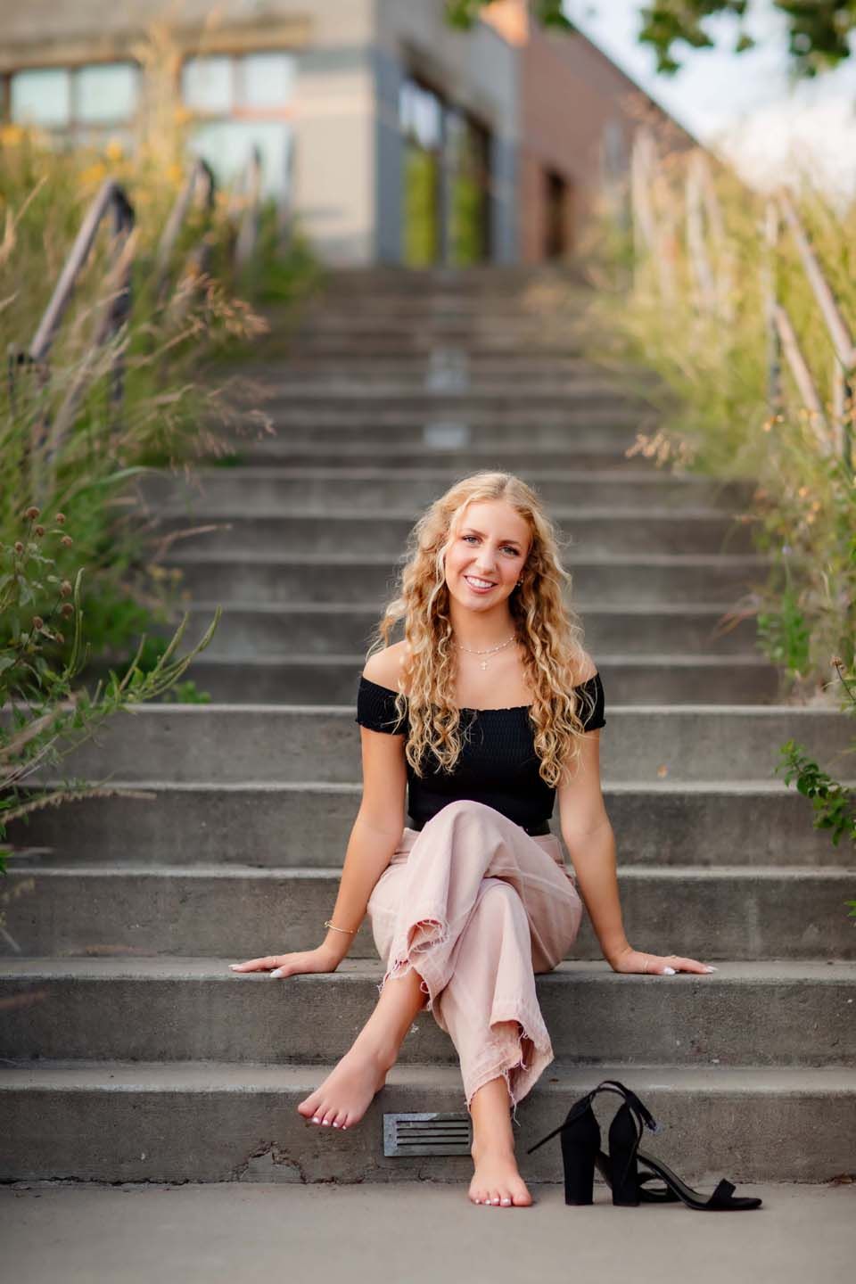 Barefoot portrait on concrete steps with shoes off, wearing casual summer outfit.