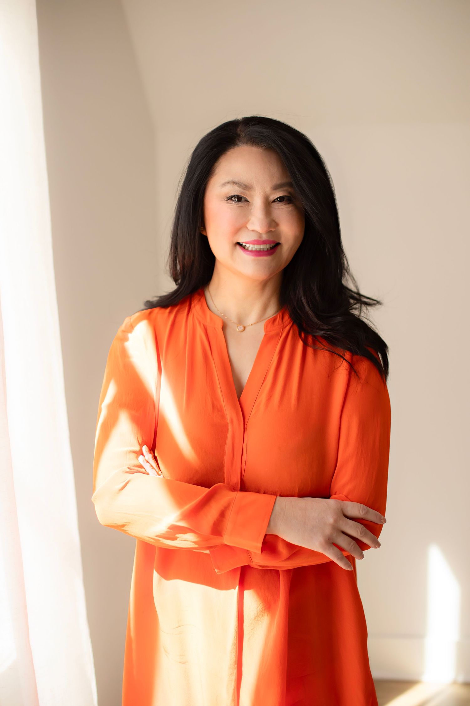 A series of photos showing a person in a vibrant orange dress posing against a light-colored wall with natural lighting.