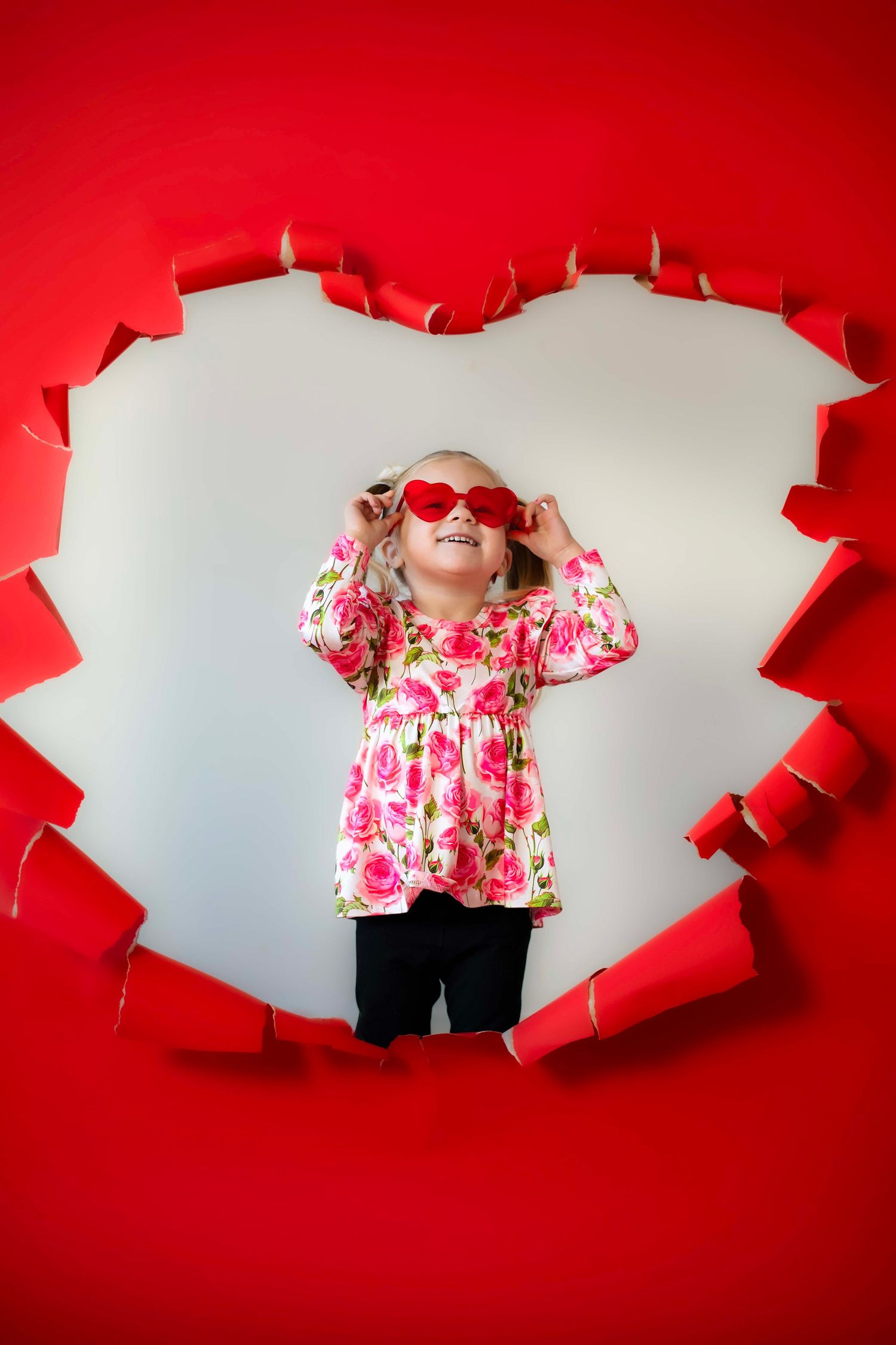 Vibrant red heart-shaped paper tear frame with fashion pose in floral dress.