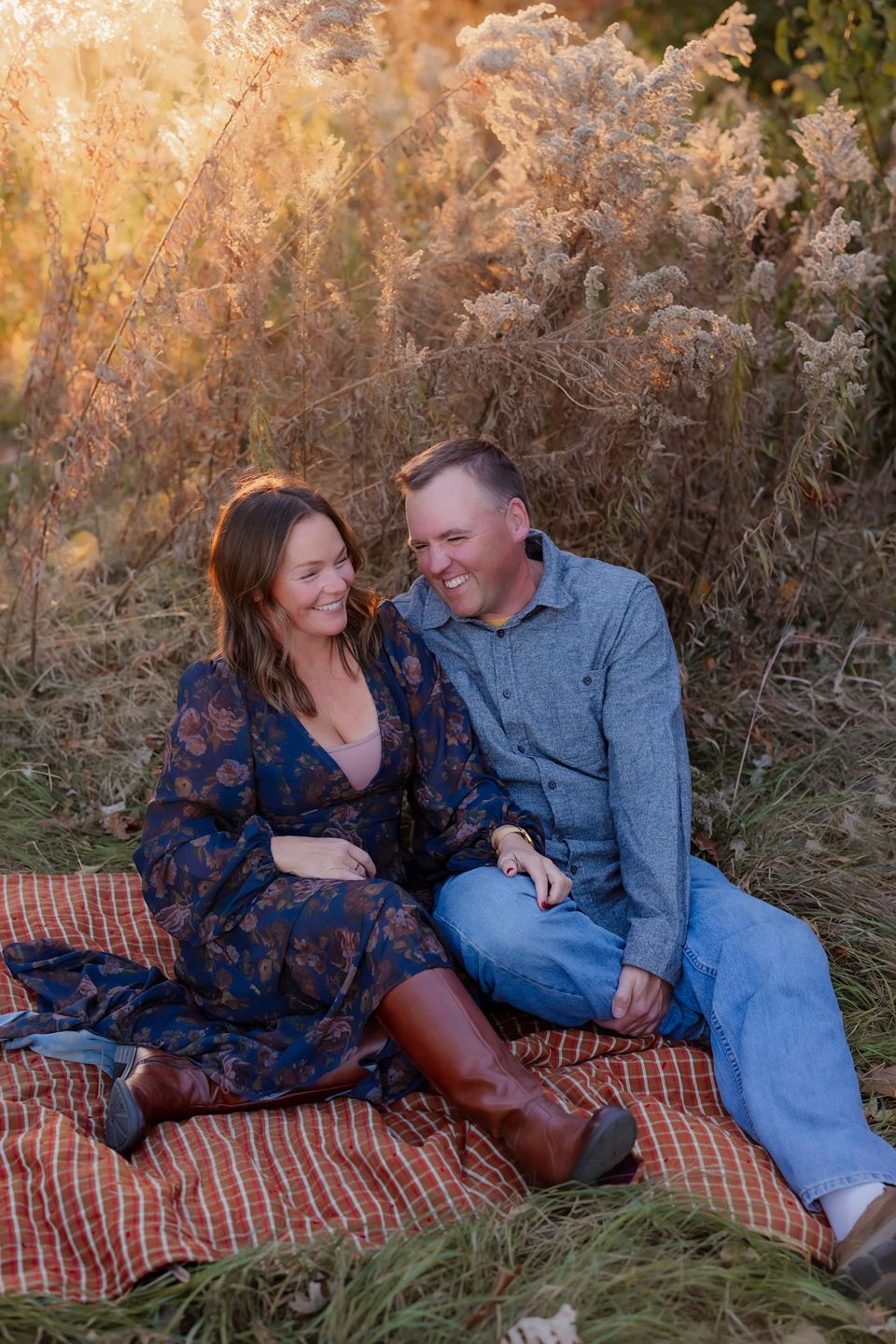 Couple sharing a romantic moment on a blanket in golden autumn grass.