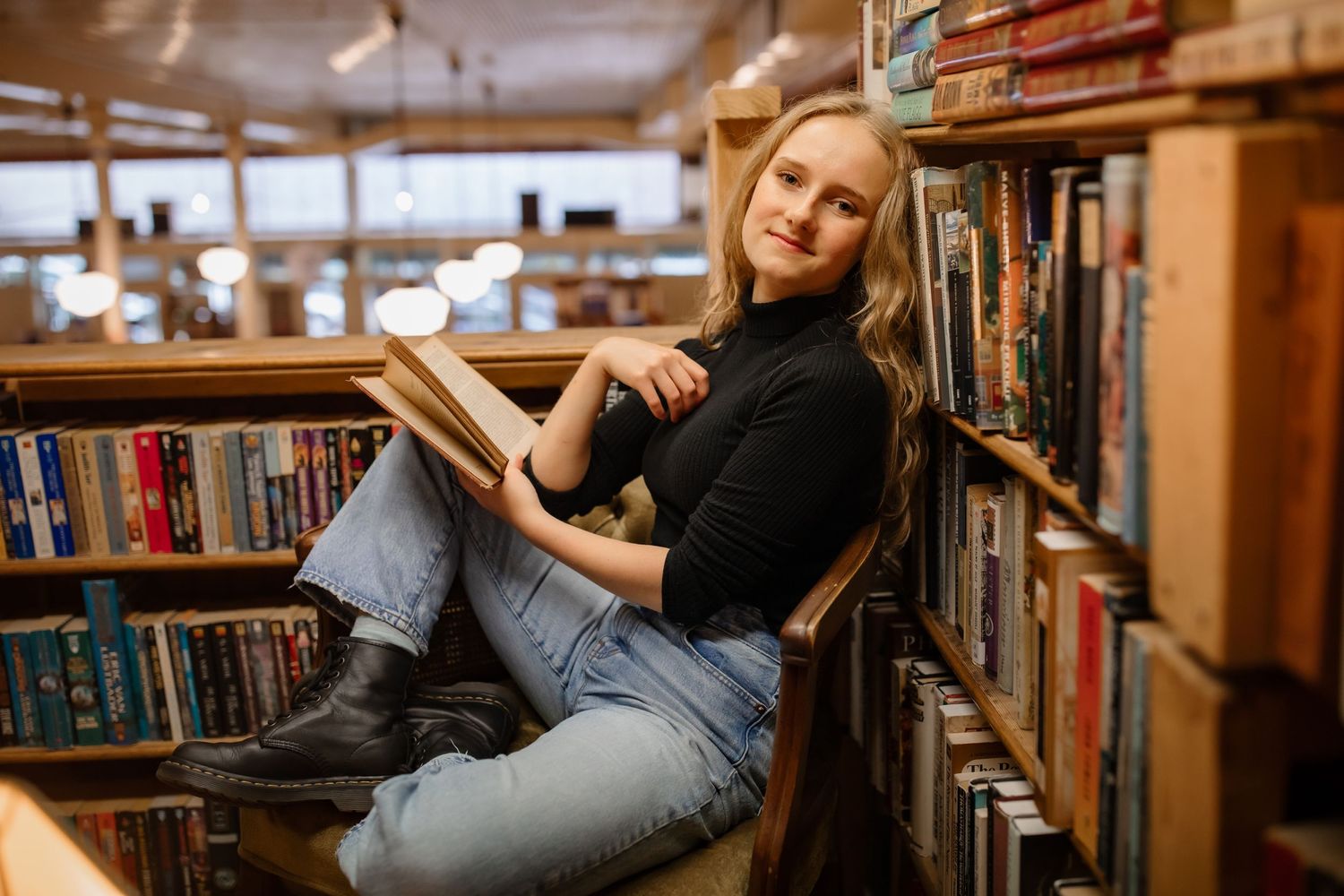 A casual reading moment in a cozy library with bookshelves and warm lighting.