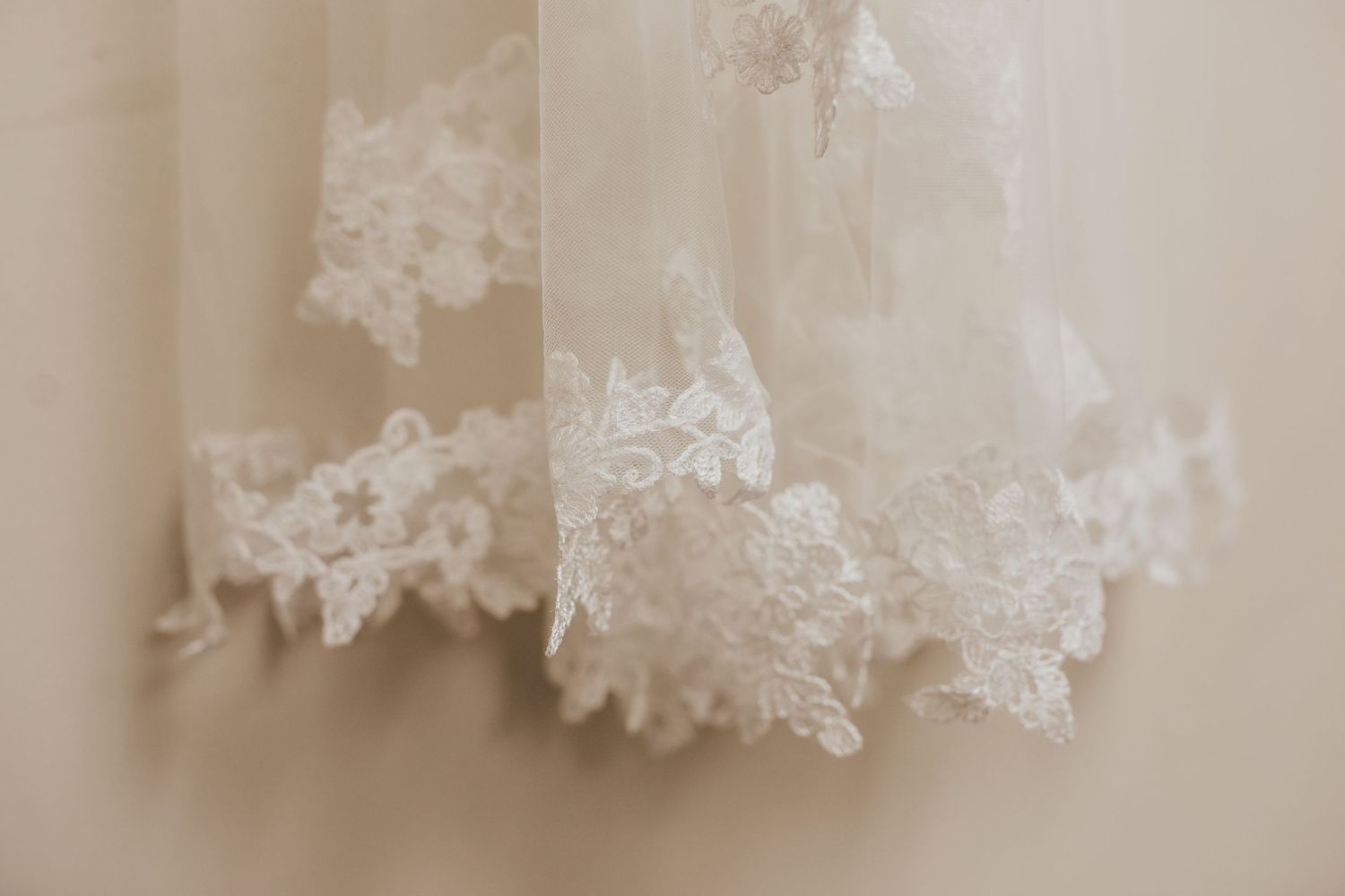 Delicate white lace trim detail of a wedding dress captured in soft focus.