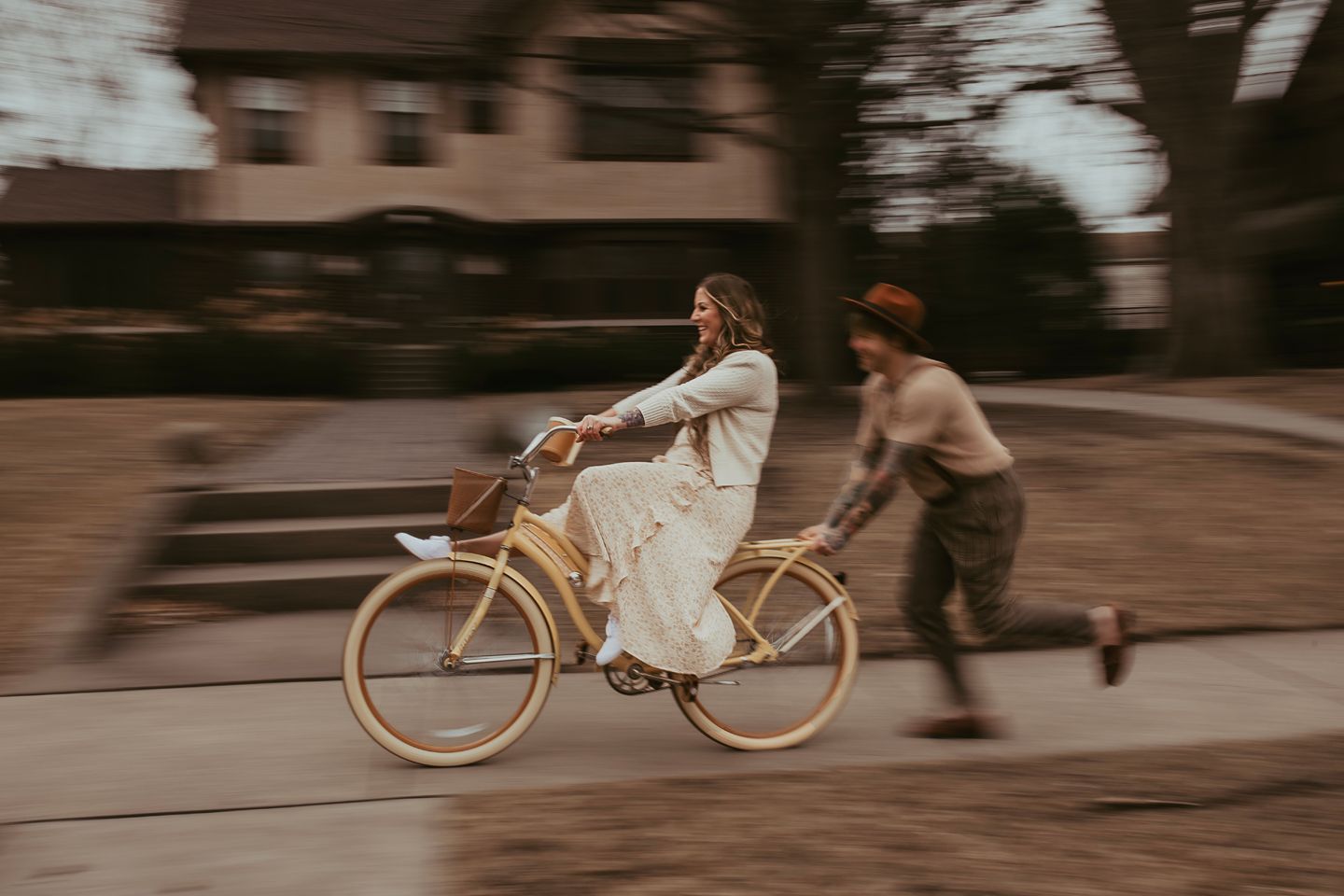 Motion-blurred shot of a person riding a vintage bicycle on a city street at dusk.