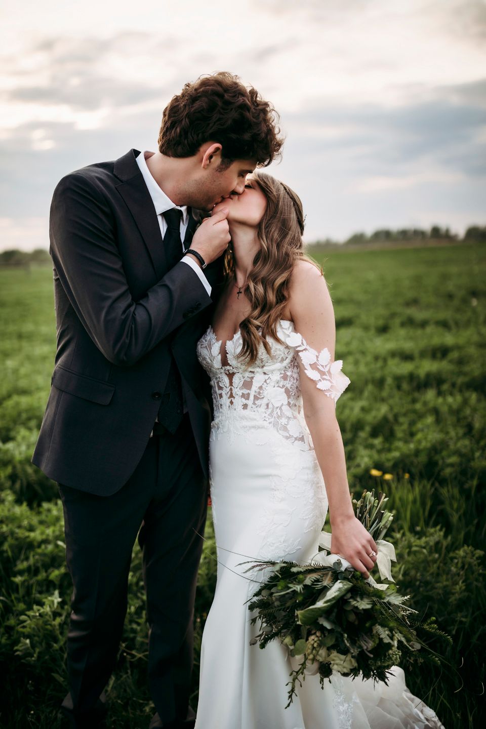 Romantic moment between newlyweds in a midwest green field with dramatic sky.