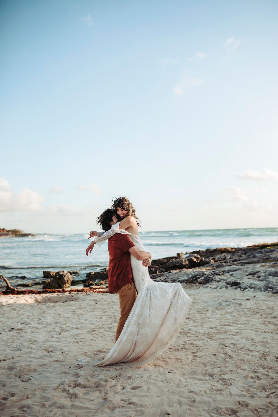 Joyful dance on sandy beach with flowing white dress catching the ocean breeze.