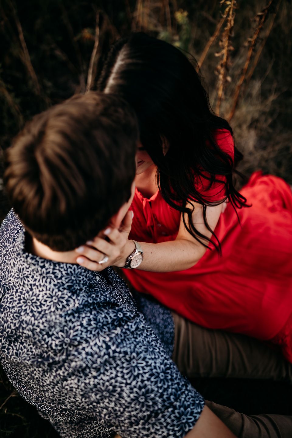 Artistic overhead view of couple in coordinated blue and red outfits sharing tender moment.