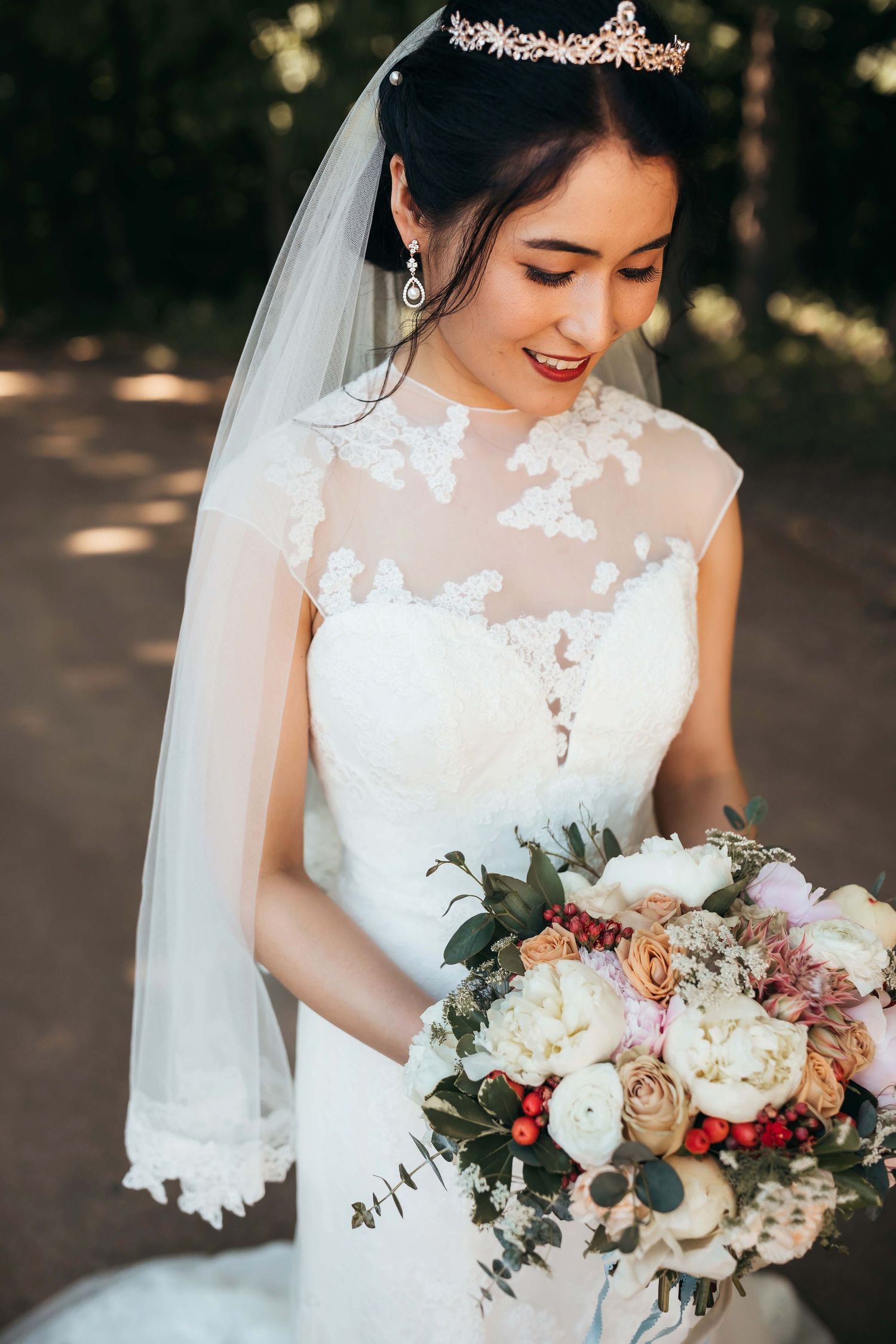 Close-up of delicate lace wedding gown detail with blush and cream floral bouquet.