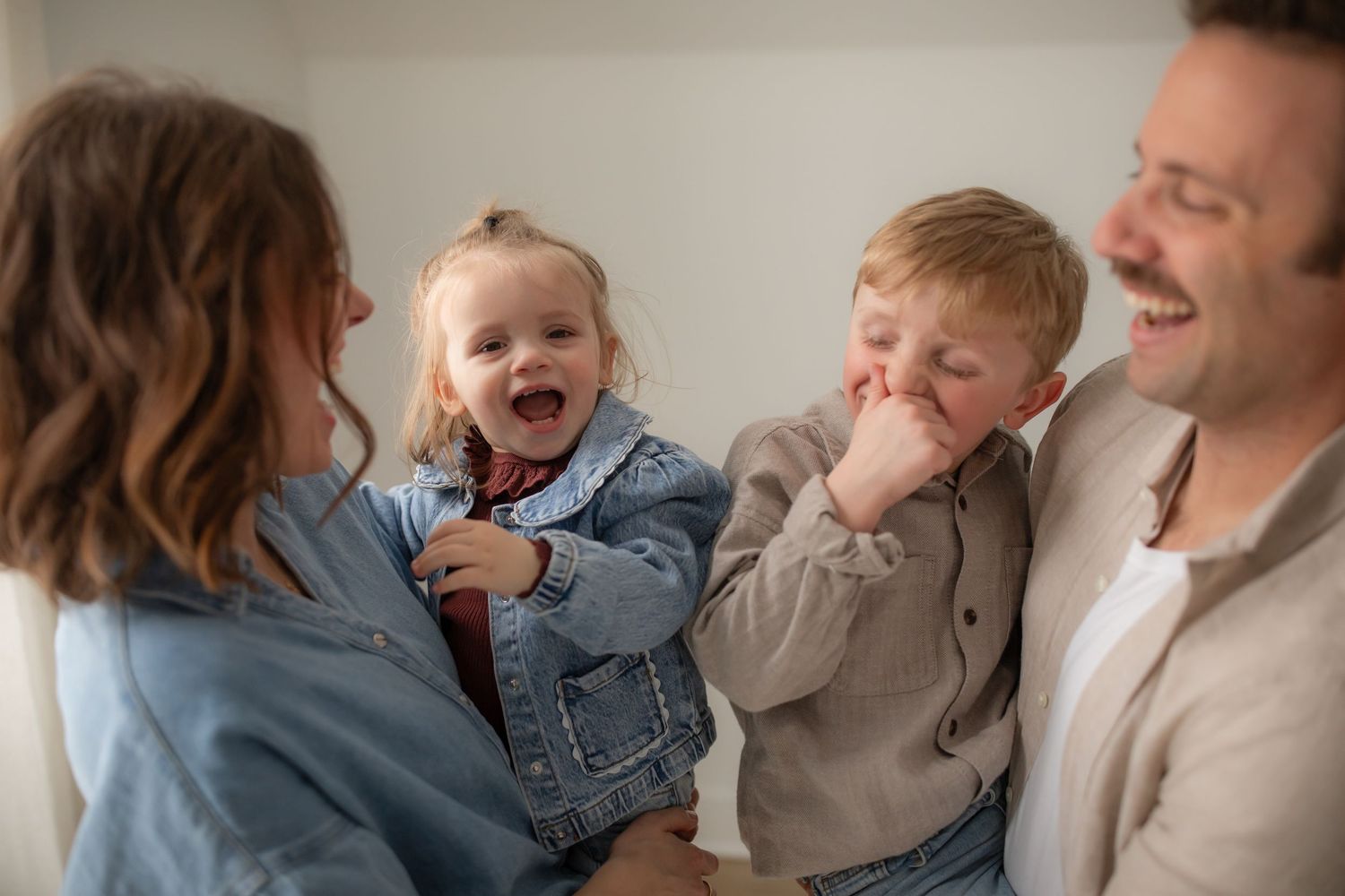 Natural candid moments of a family laughing and embracing during an indoor photo session.