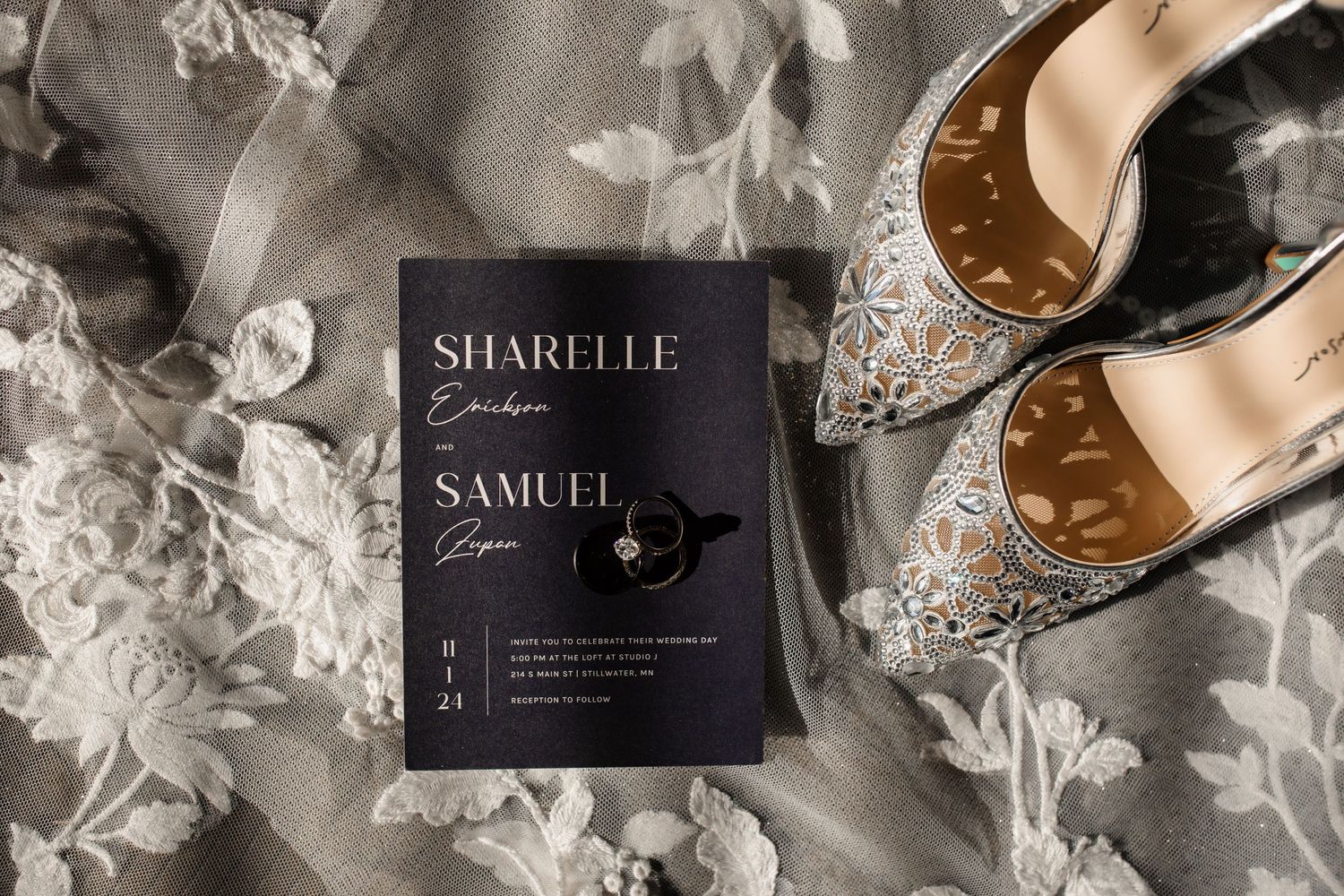 Wedding invitation and ornate bridal shoes arranged on a light fabric background.