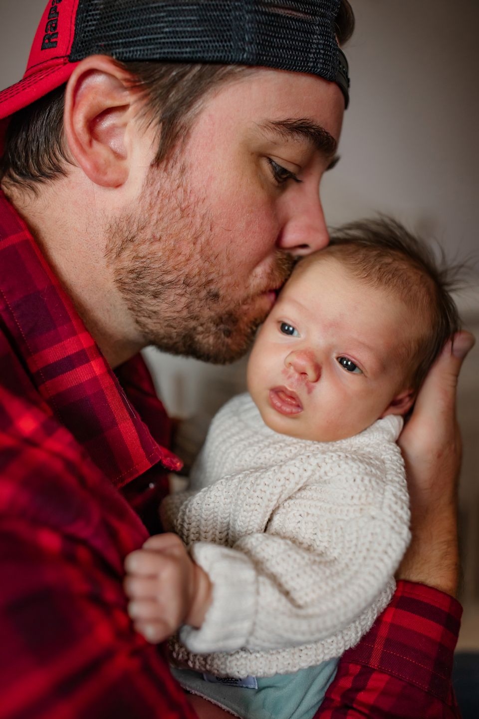 A sweet bonding moment captured in front of a white crib with soft natural lighting.