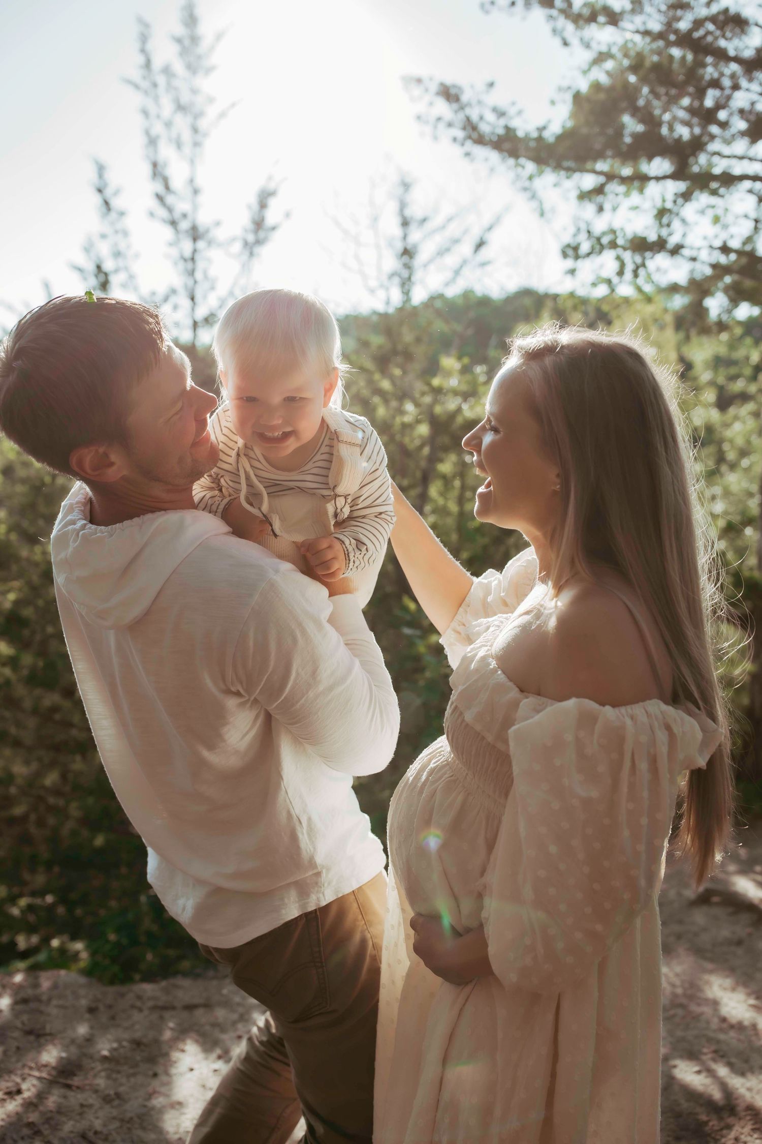 A joyful family moment captured in golden sunlight against a forest backdrop.