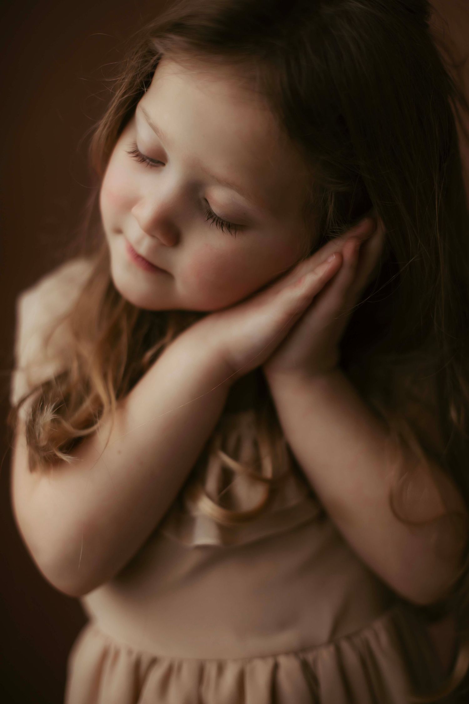 Series of artistic portraits showing a child in a dreamy pose with hands near face against dark background.