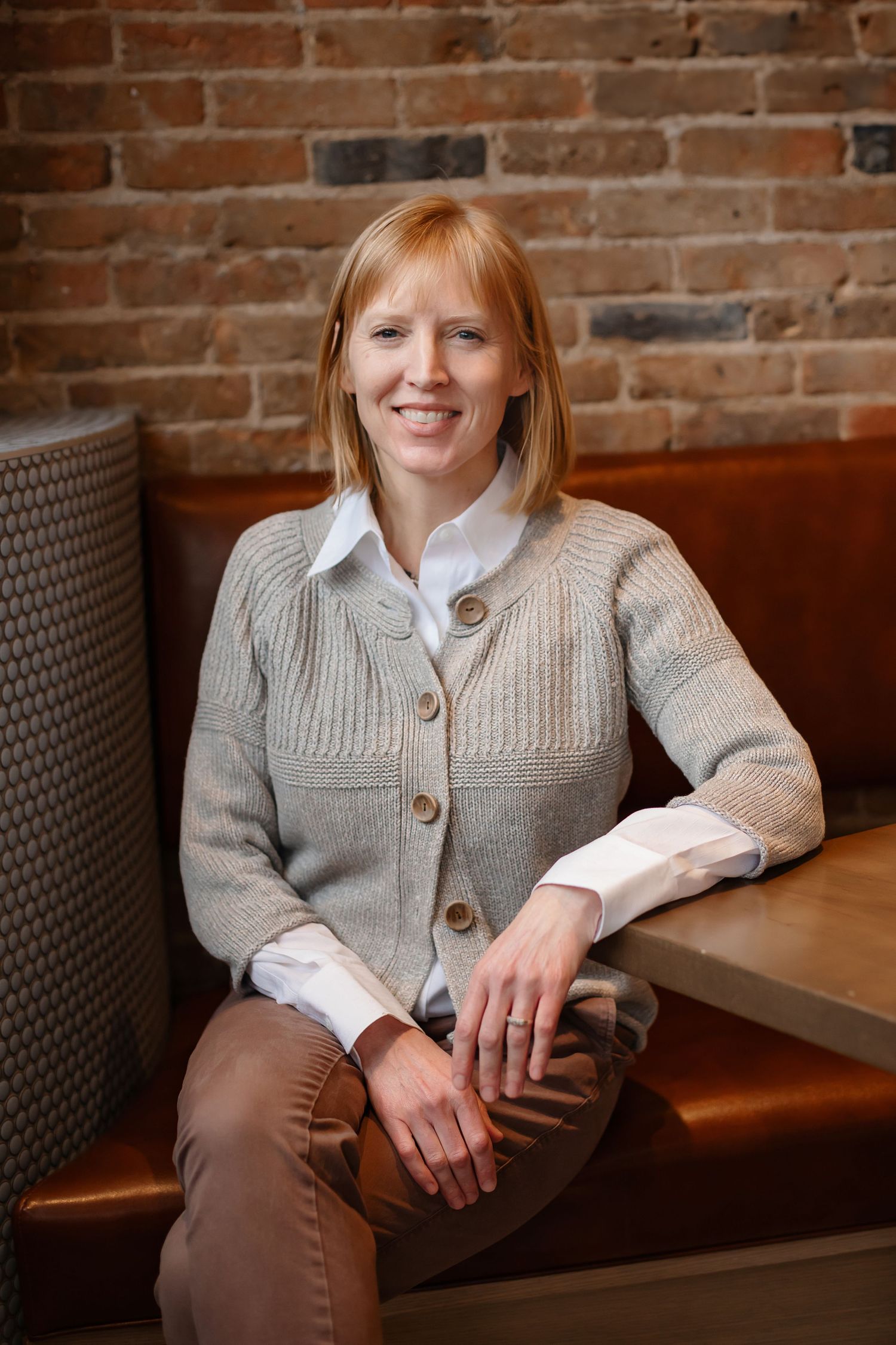 Casual business portrait in coffee shop with exposed brick wall background.
