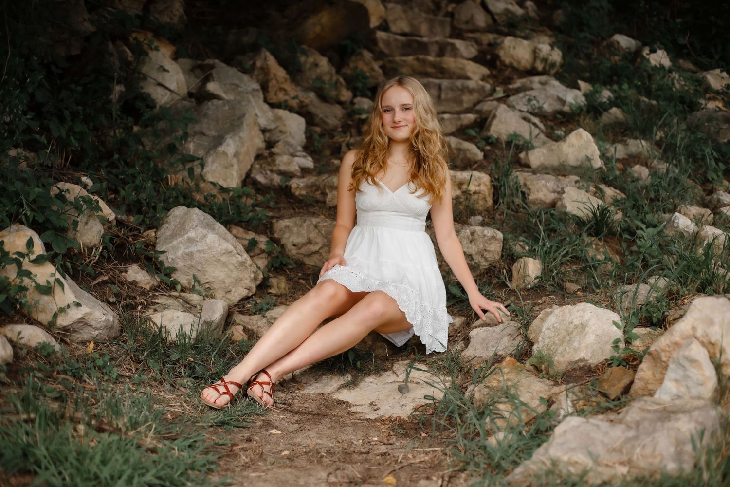 A ethereal outdoor portrait featuring a white sundress against natural rocky backdrop in warm lighting.