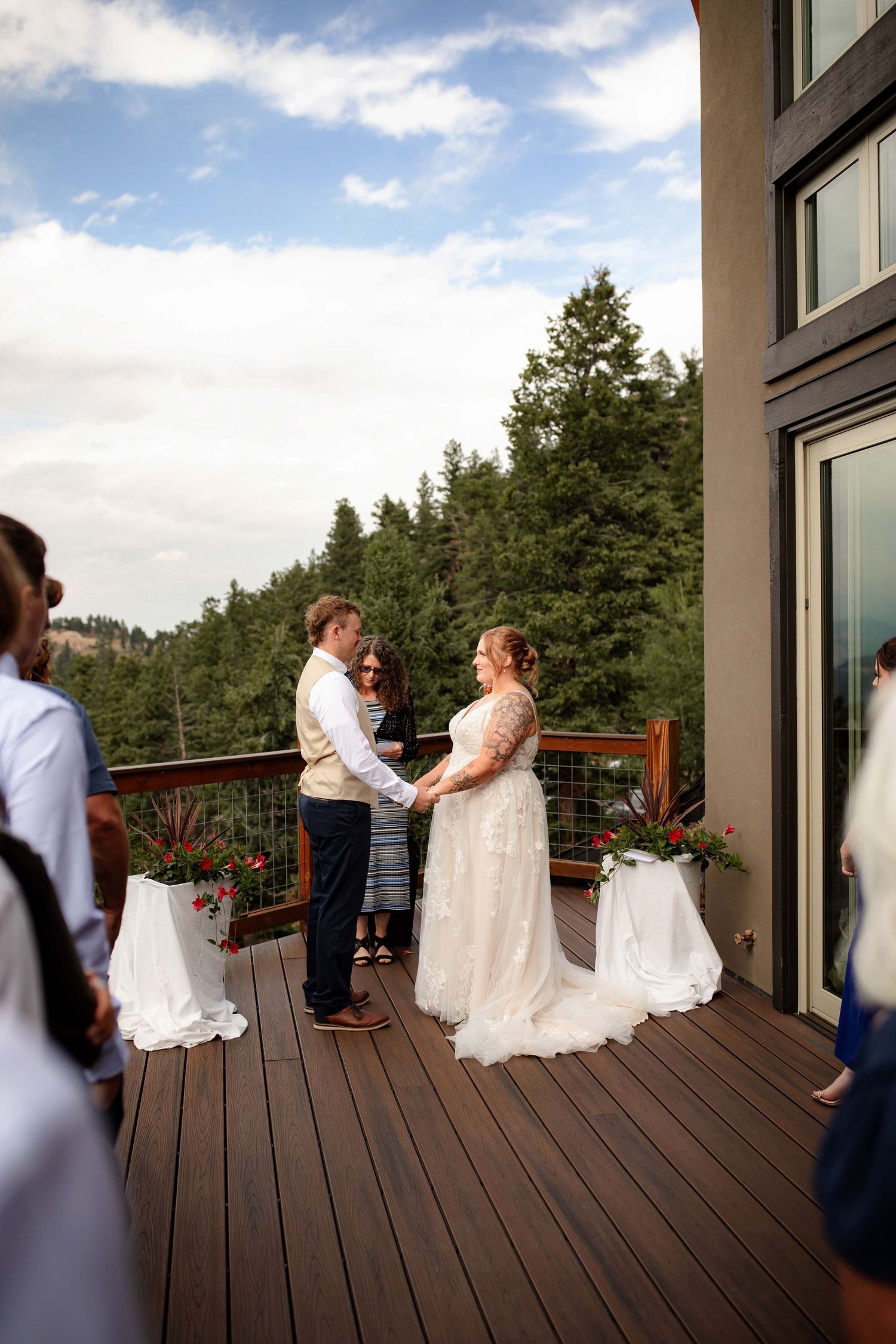Wedding couple shares an intimate dance on a wooden deck surrounded by mountain scenery and evergreen trees.