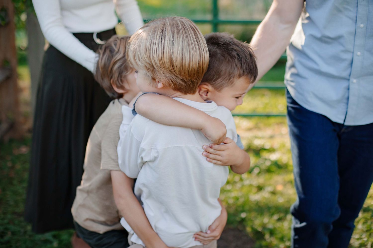 Two young children share a warm embrace outdoors in natural lighting.