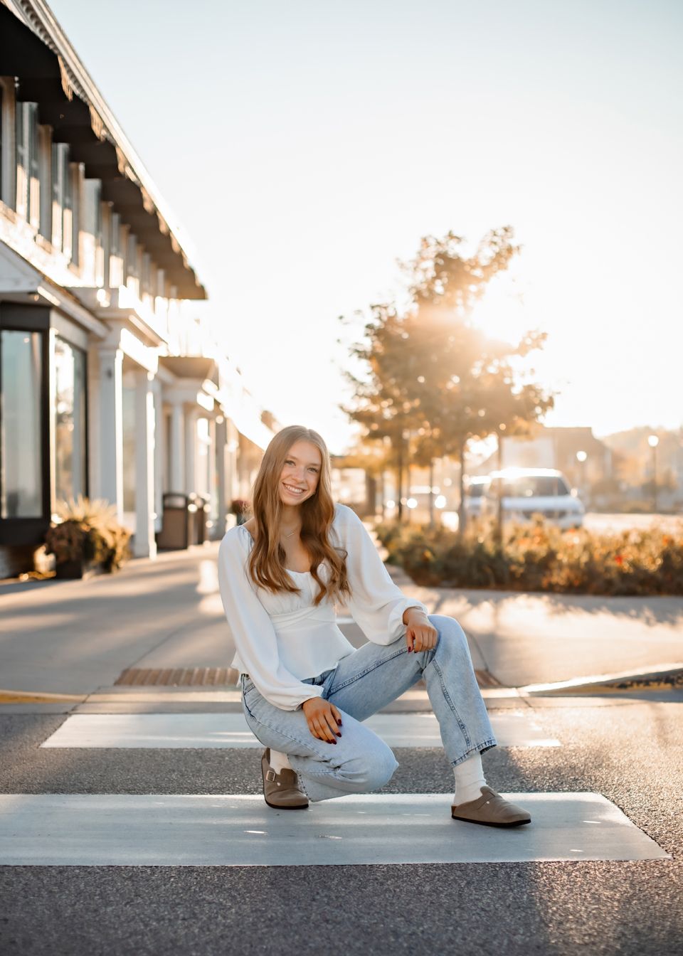 Street fashion photo at sunset with casual outfit on crosswalk with modern buildings.