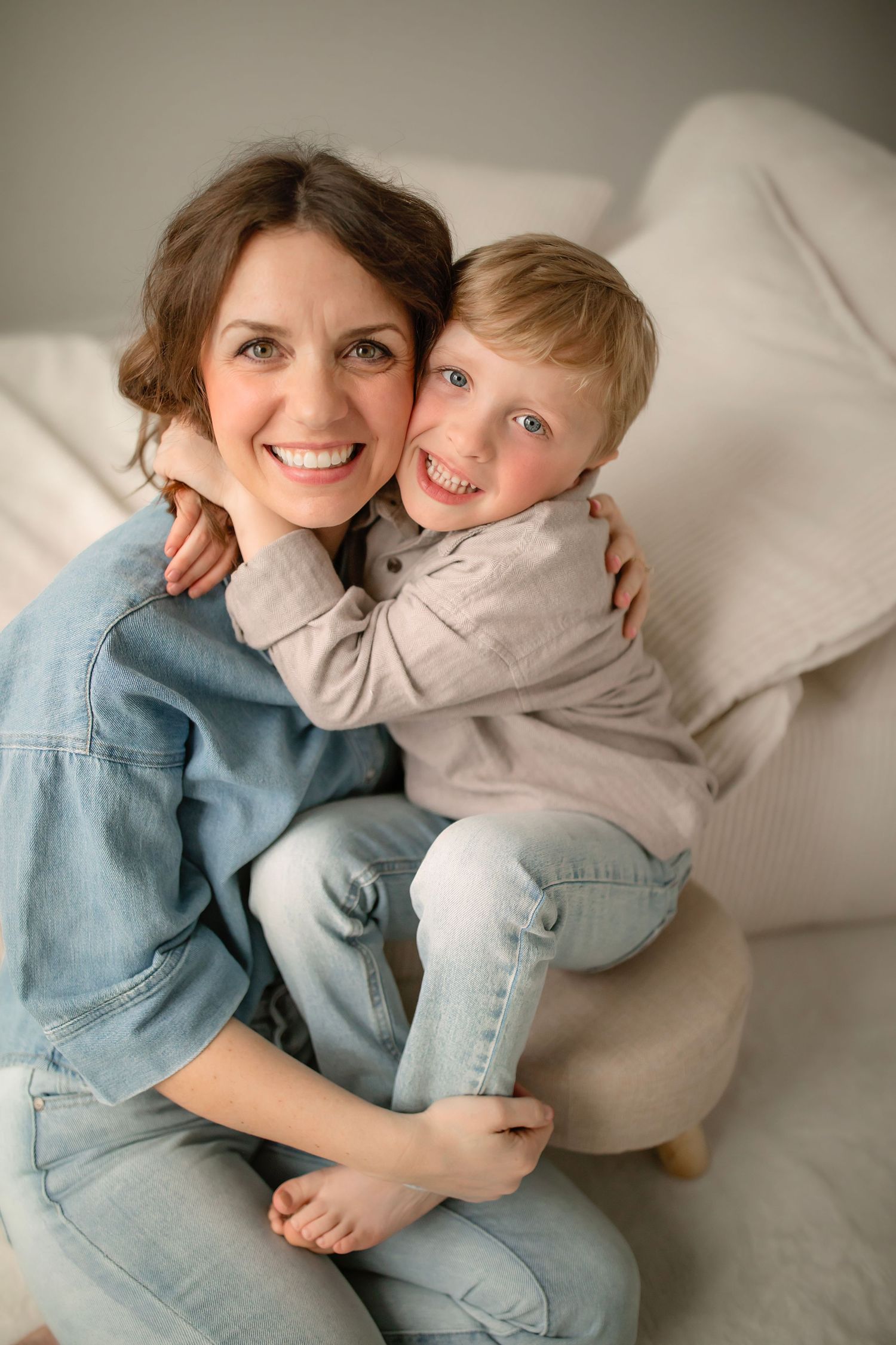 Intimate lifestyle photography capturing joyful moments between family members on white furniture.