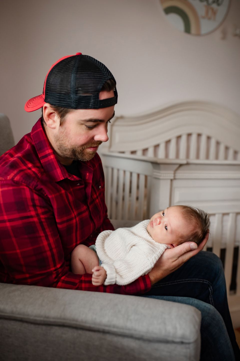 A heartwarming moment in a nursery featuring a grey armchair and white wooden crib.